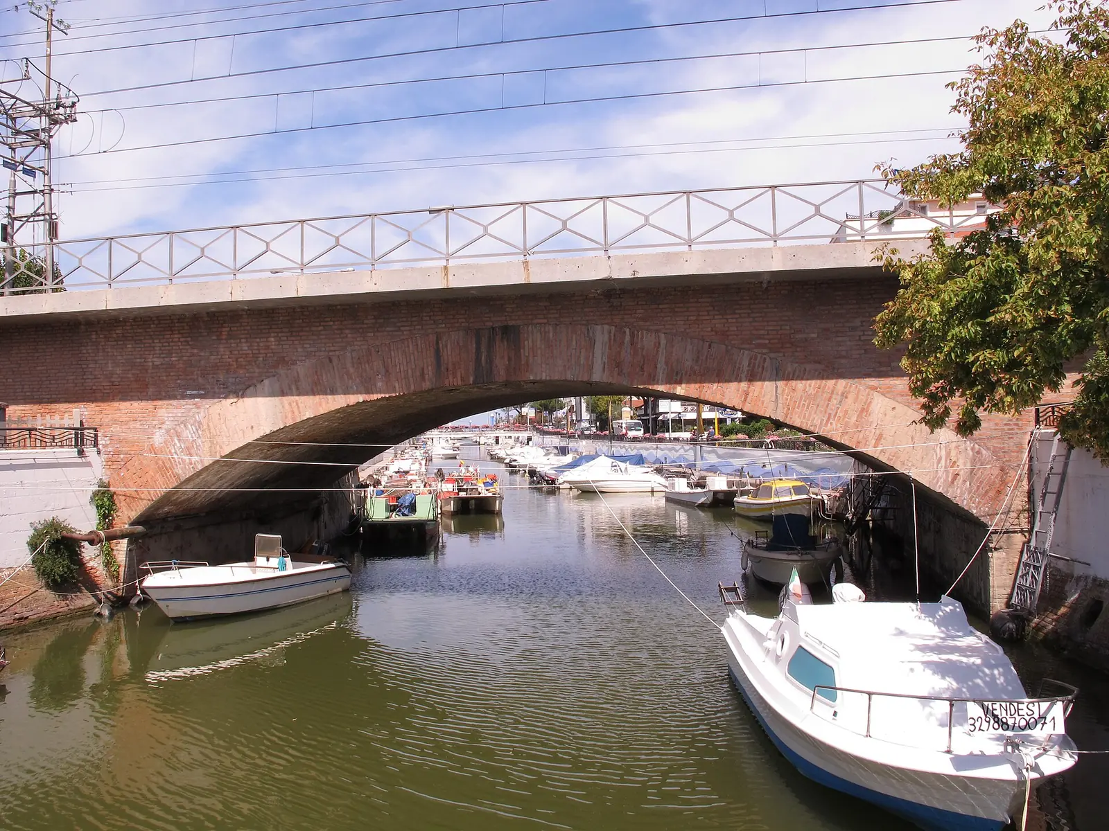 Un ponte in mattoni sul porto canale di Riccione, con barche a motore ormeggiate sotto l'arcata