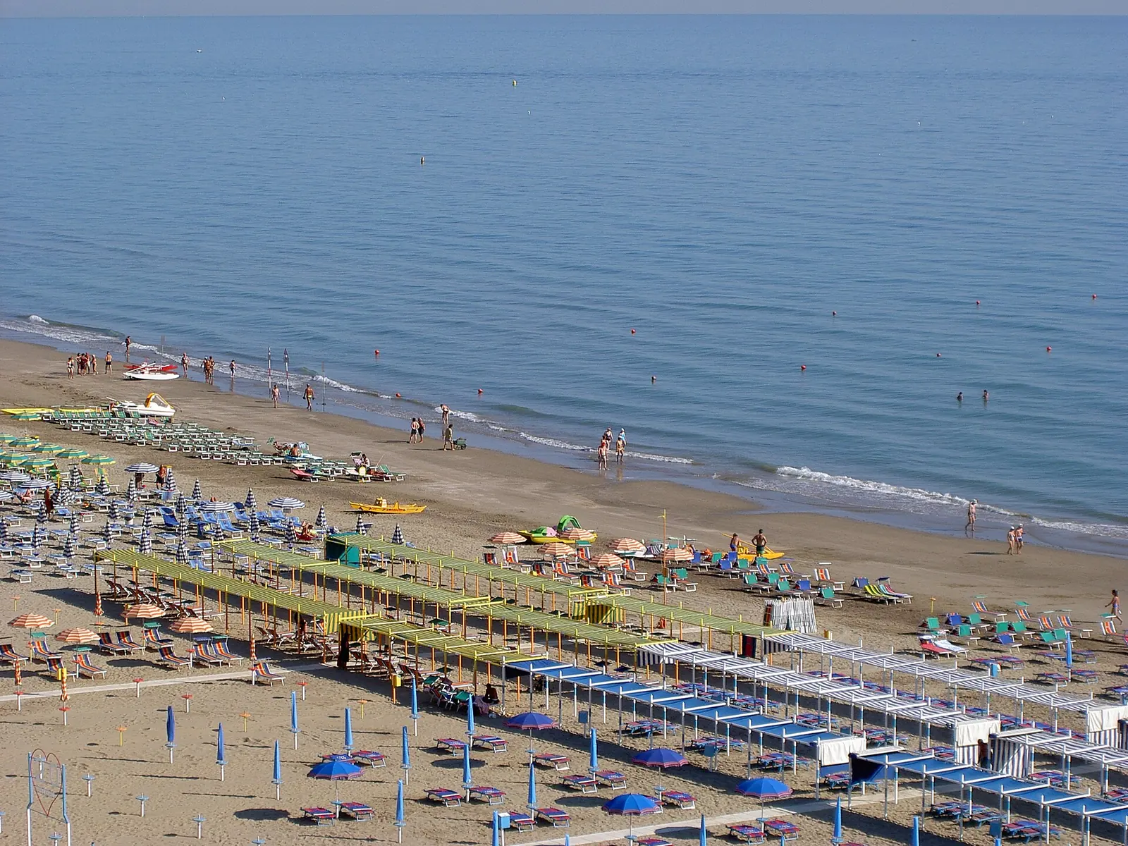Vue d'en haut de la plage de Riccione, avec les rangées de parasols, les tentes et la mer calme