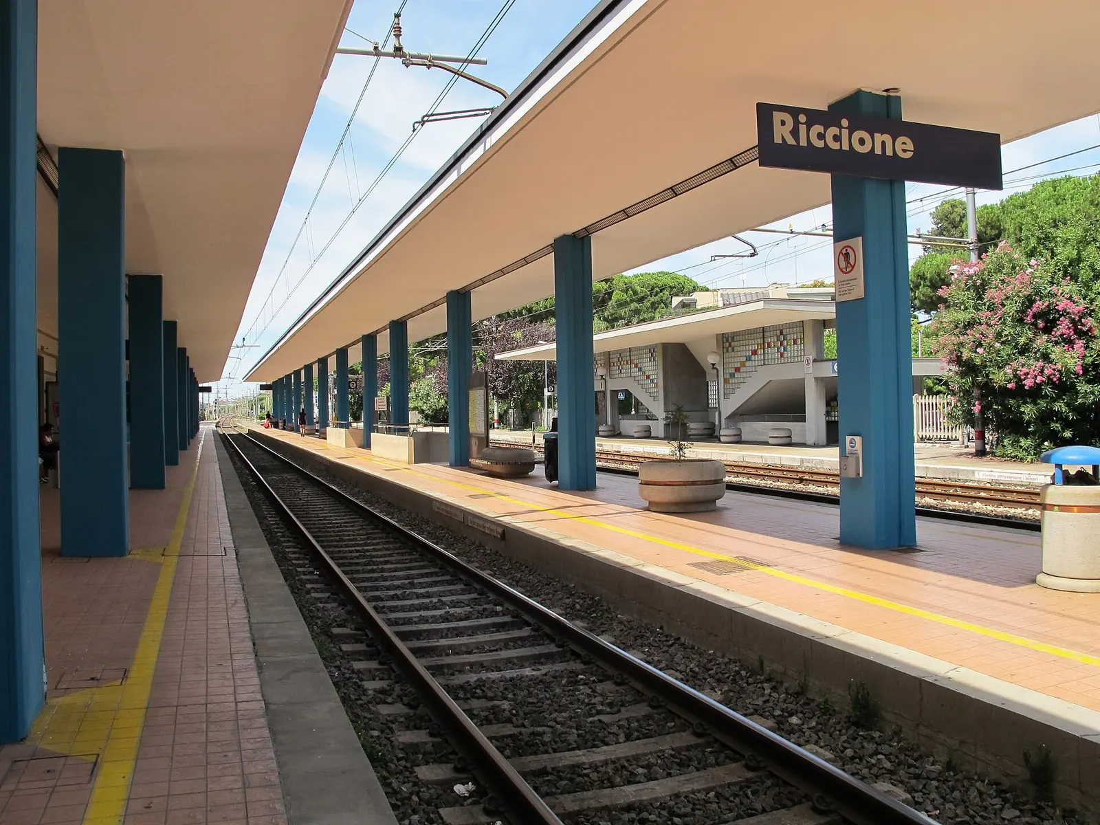 Le quai de la gare de Riccione avec la marquise, les piliers bleus et le panneau portant le nom de la gare