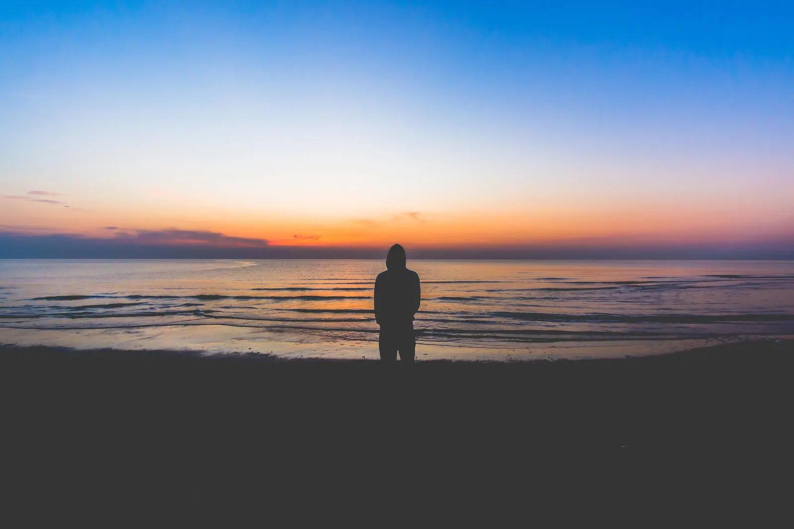 Aube sur la mer Adriatique depuis la plage de Riccione, avec le ciel passant du bleu à l'orange