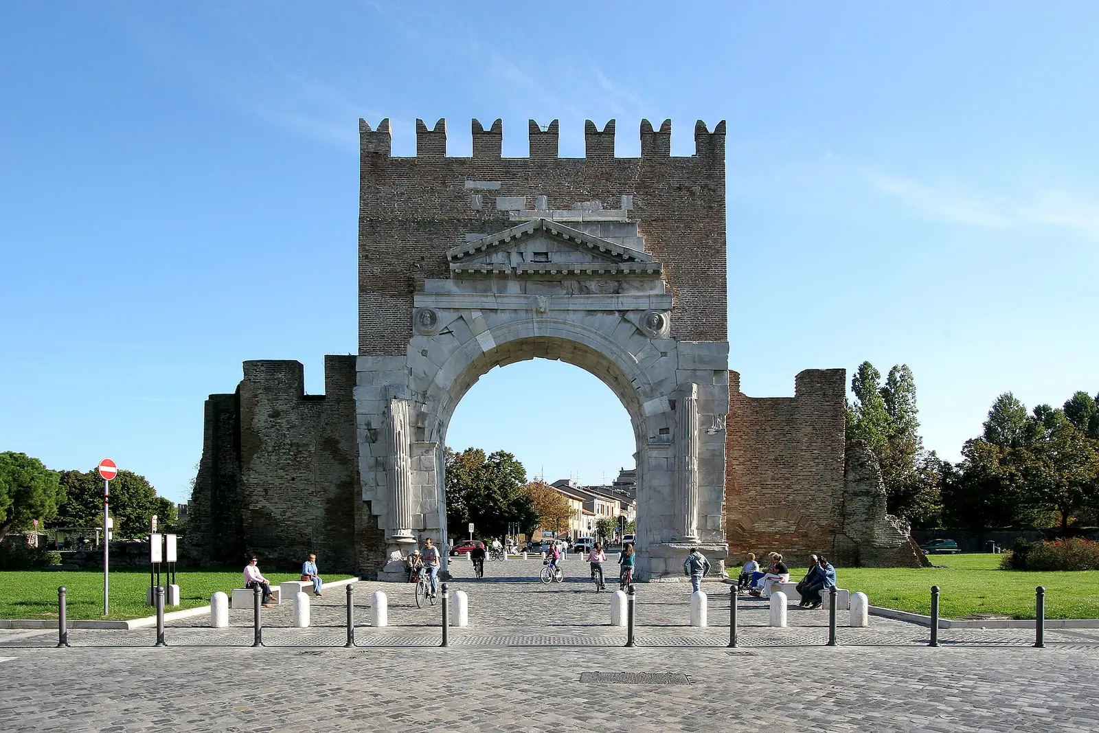 L'Arco di Augusto de Rimini vu de face, avec les murs en brique de chaque côté et les petites colonnes de pierre devant