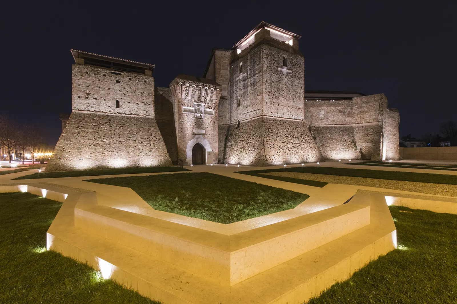 Castel Sismondo à Rimini de nuit, avec les tours éclairées et les massifs géométriques du jardin au premier plan