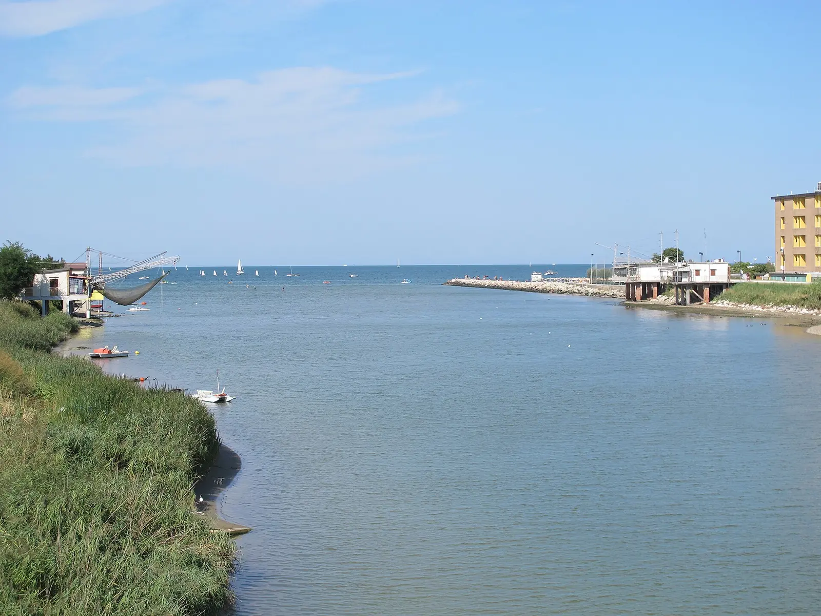 La foce del fiume Marecchia a Rimini, con una grande rete da pesca a sinistra, il molo e le barche a vela verso il mare
