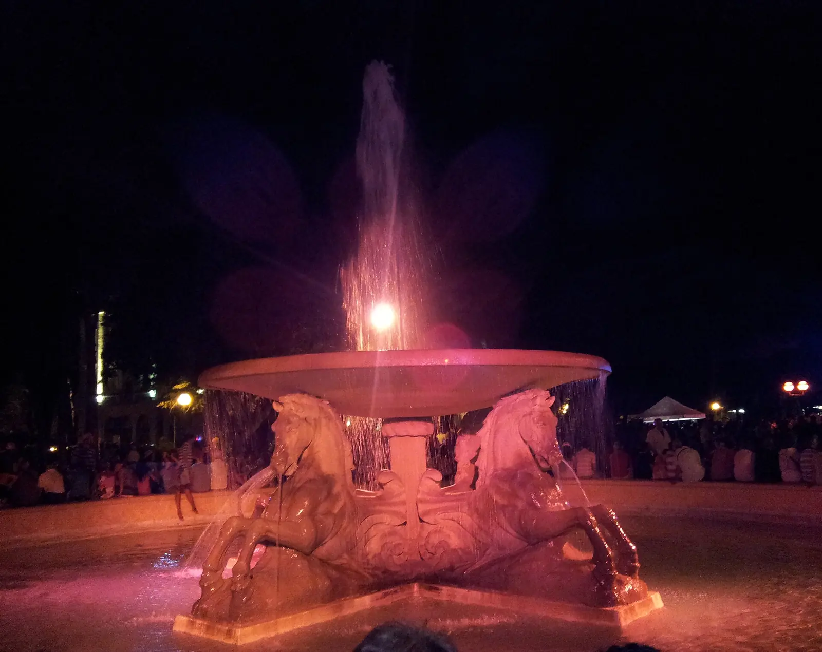 La Fontana dei Quattro Cavalli à Rimini éclairée en rose de nuit, avec le jet d'eau au centre