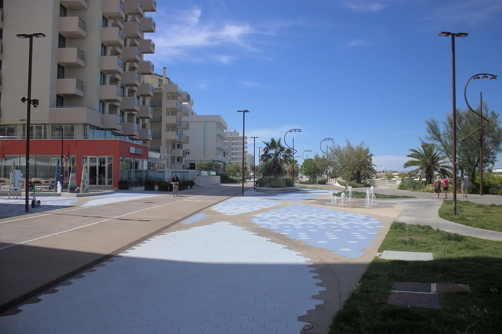 Il lungomare di Miramare a Rimini, con la pista ciclabile, la pavimentazione a disegni azzurri, i giochi d'acqua e le palme