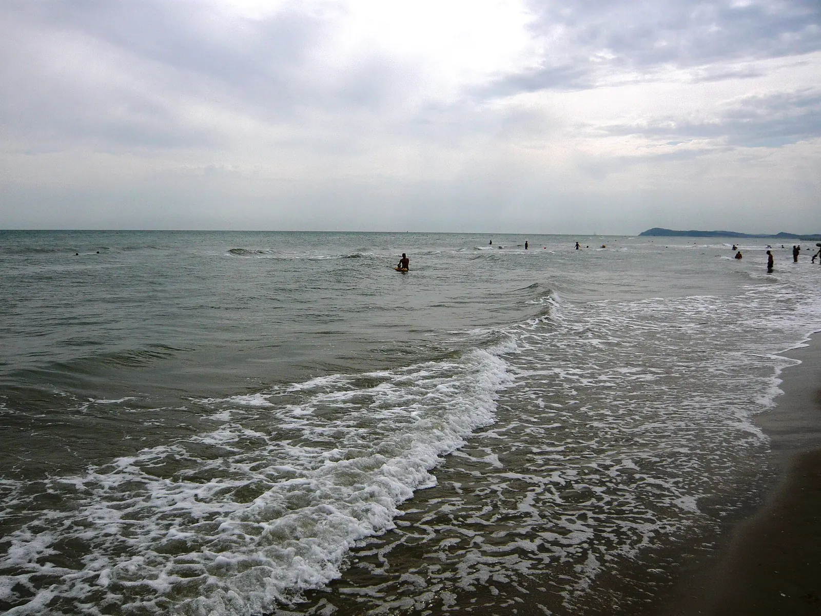 Das Meer von Rimini, wo im Sommer Boabay verankert wird, an einem bewölkten Tag mit Wellen am Ufer und dem Vorgebirge im Hintergrund