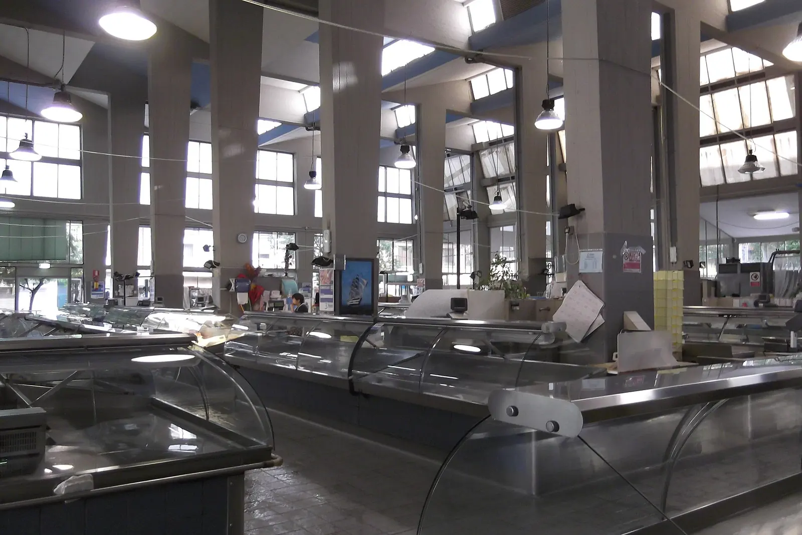 Die leeren Fischstände des Mercato Coperto in Rimini zwischen Betonpfeilern, hängenden Lampen und großen Fenstern