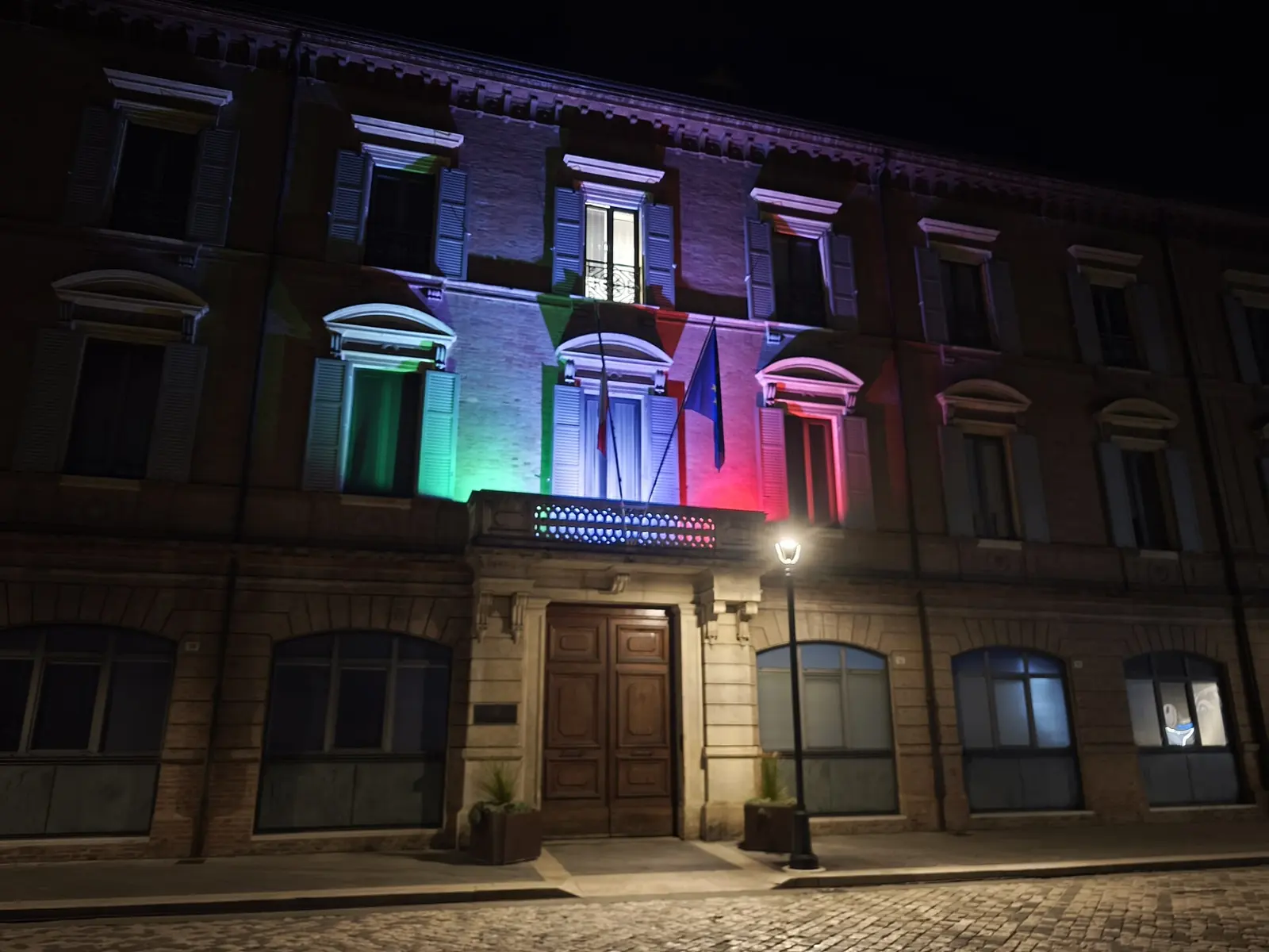 Palazzo Garampi, sede del Comune di Rimini, di sera con la facciata illuminata dai colori del tricolore