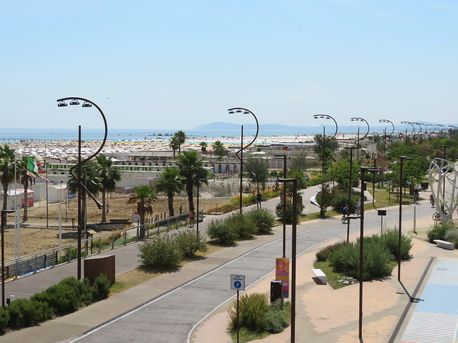 Il Parco del Mare di Rimini dall'alto, con la strada ciclopedonale curva, i lampioni ricurvi, le palme e il mare