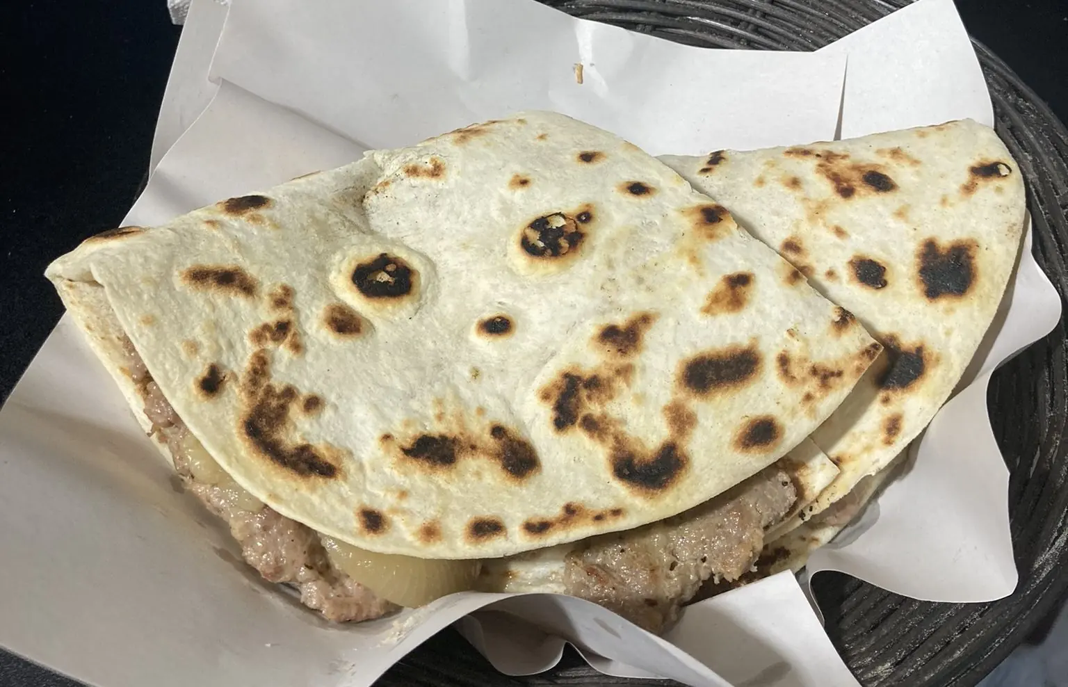 Ein frisch gebackener Cassone, eine zusammengeklappte und gefüllte Piadina, auf Papier in einem Körbchen serviert