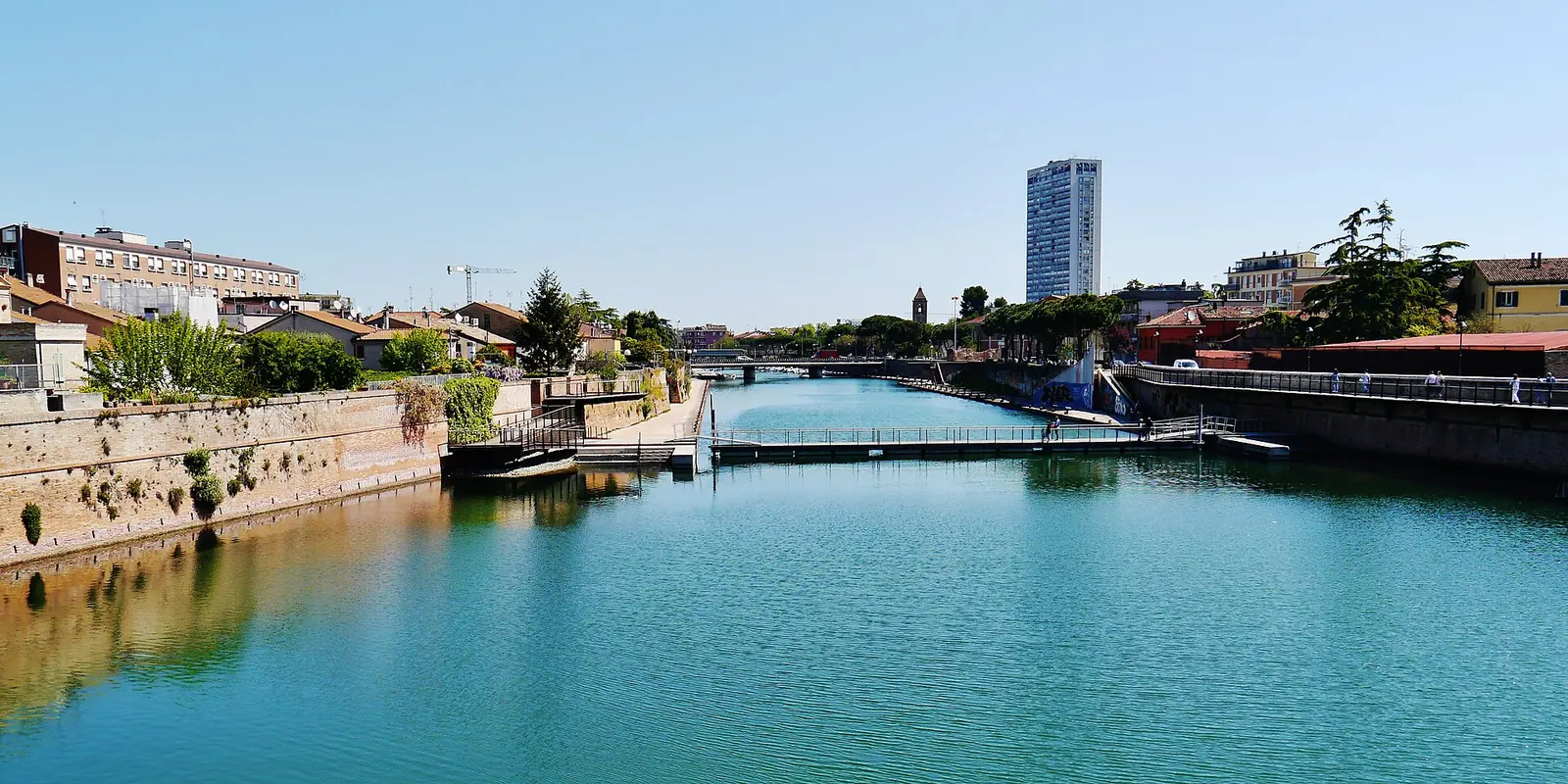 Le port-canal de Rimini avec les rives en brique, une passerelle piétonne et le gratte-ciel en arrière-plan