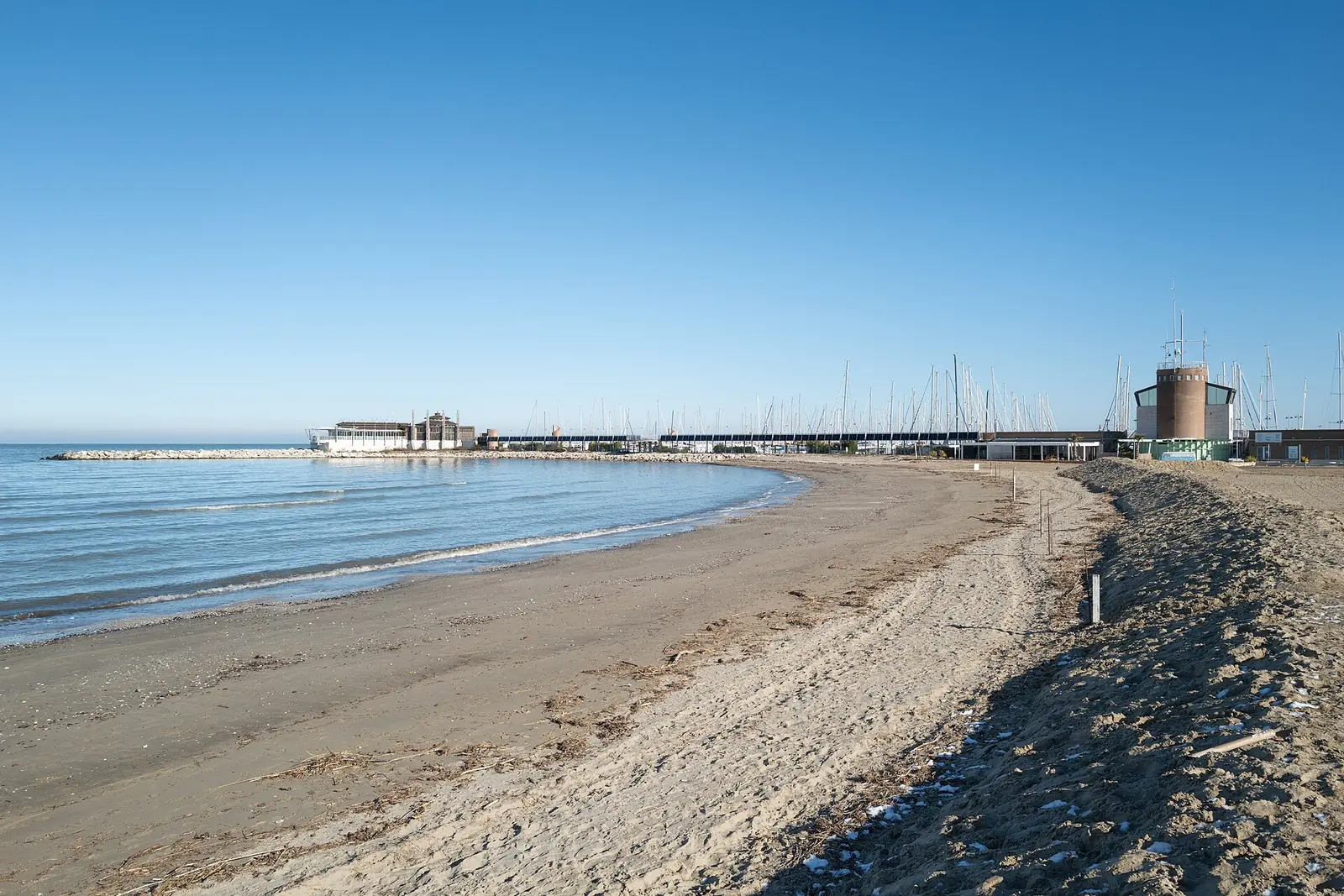 Der Strand von Rimini im Winter mit verlassenem Ufer, klarem Himmel und Yachthafen im Hintergrund