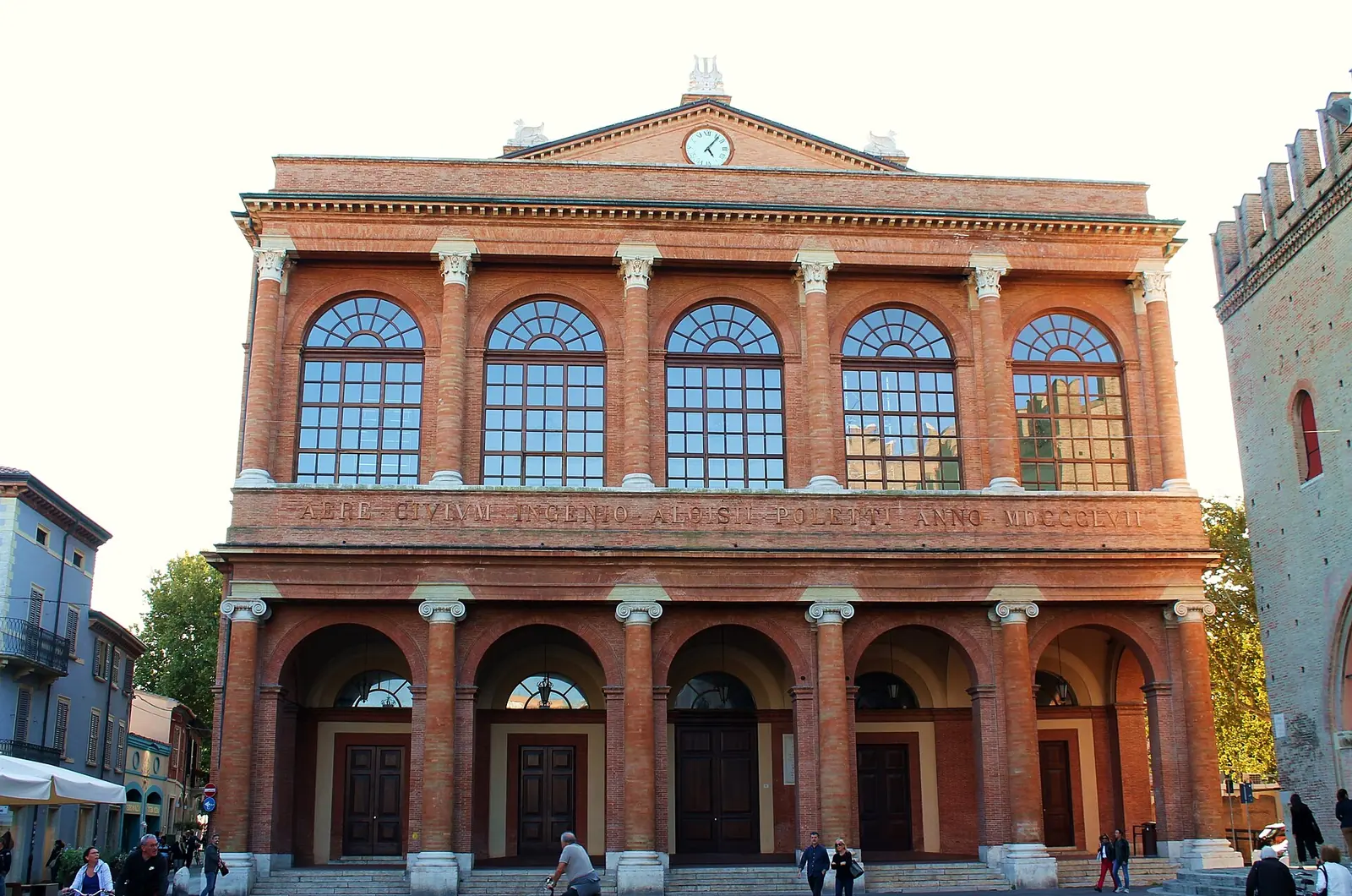 La facciata in laterizio del Teatro Galli a Rimini, con il portico ad archi, le grandi finestre e il timpano con l'orologio