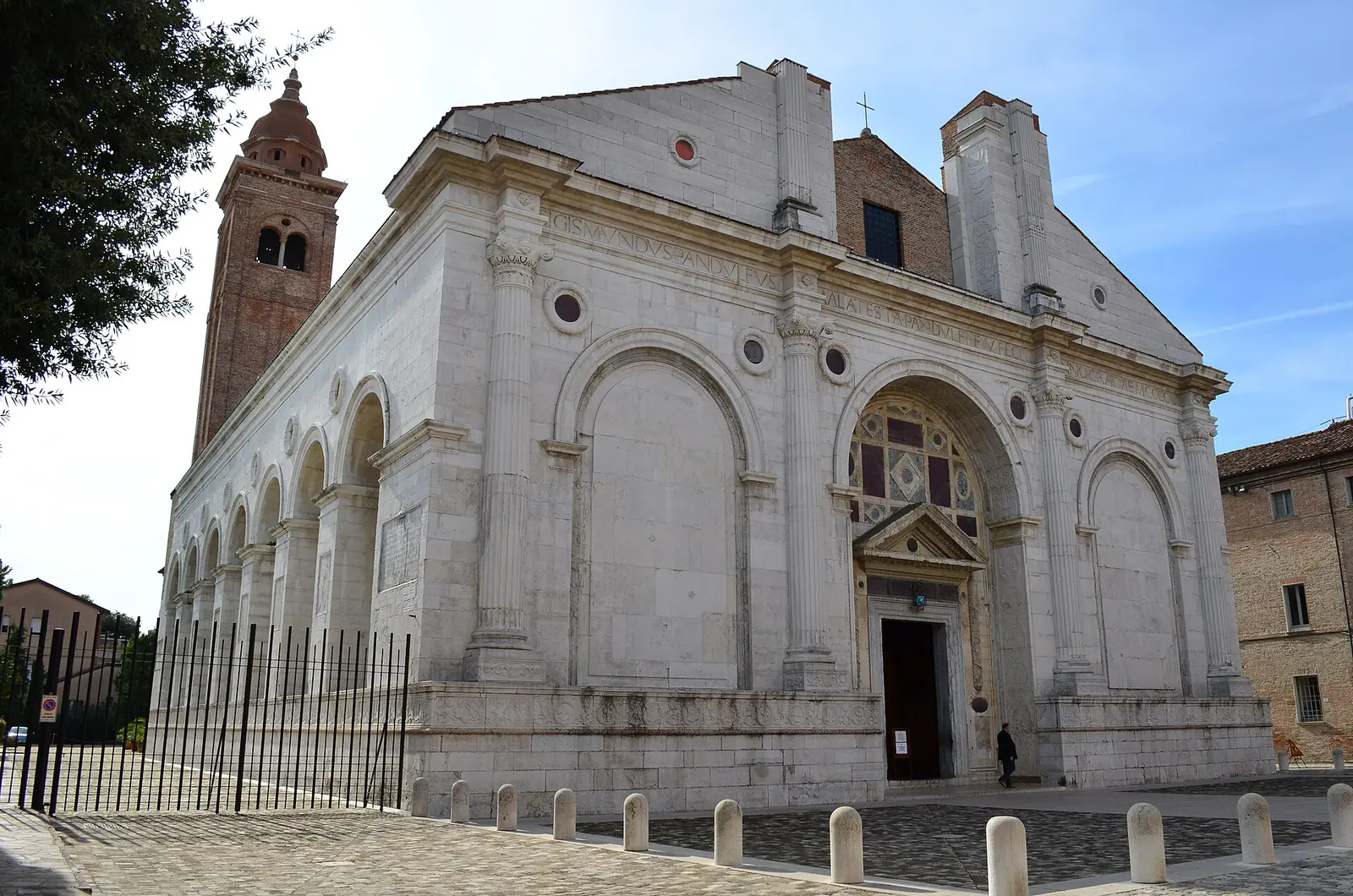 La facciata in marmo bianco del Tempio Malatestiano di Rimini, con il campanile e una persona sul sagrato