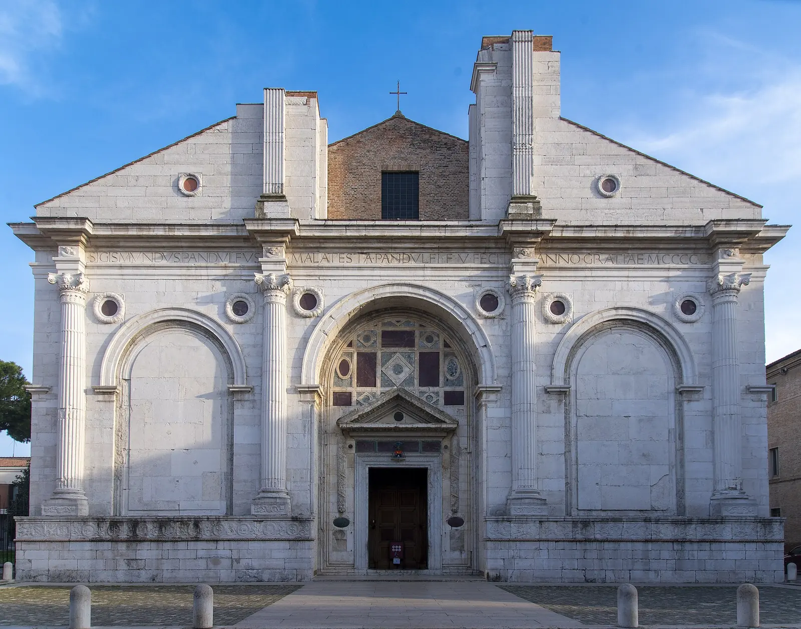 La facciata in pietra bianca del Tempio Malatestiano di Rimini, con le colonne, gli archi ciechi e il portale centrale