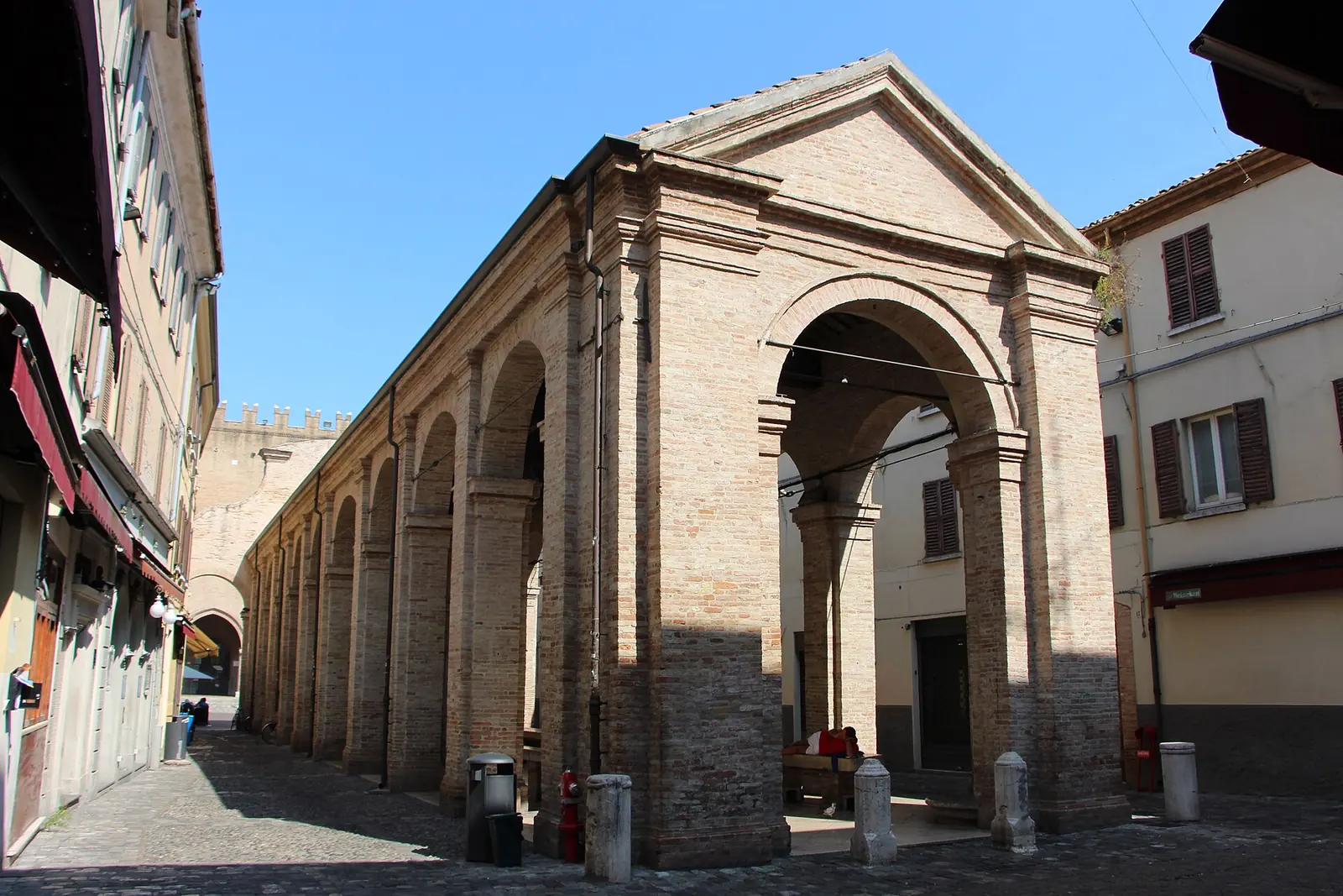 Die Backsteinloggia der Vecchia Pescheria in Rimini von der Seite mit Bögen und Säulen unter blauem Himmel