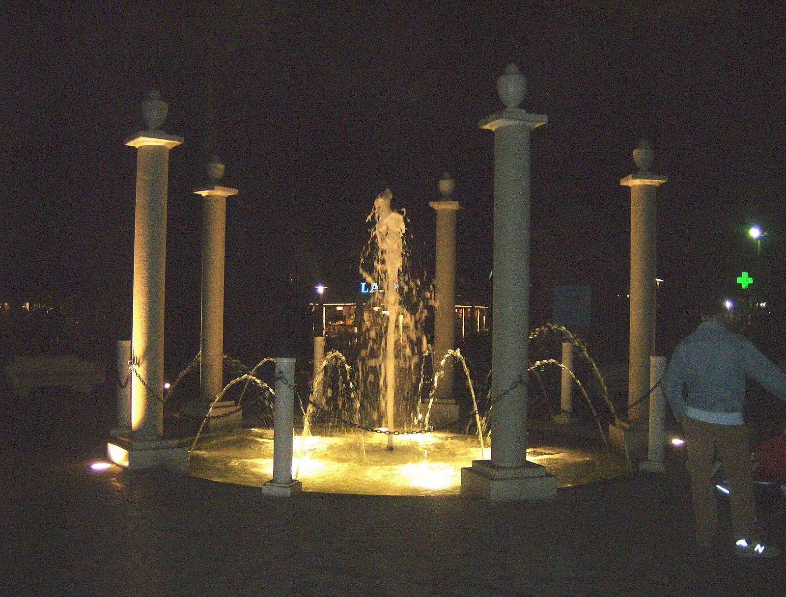 Der nachts beleuchtete Brunnen der Rotonda Primo Maggio in Milano Marittima mit Steinsäulen und Wasserstrahlen