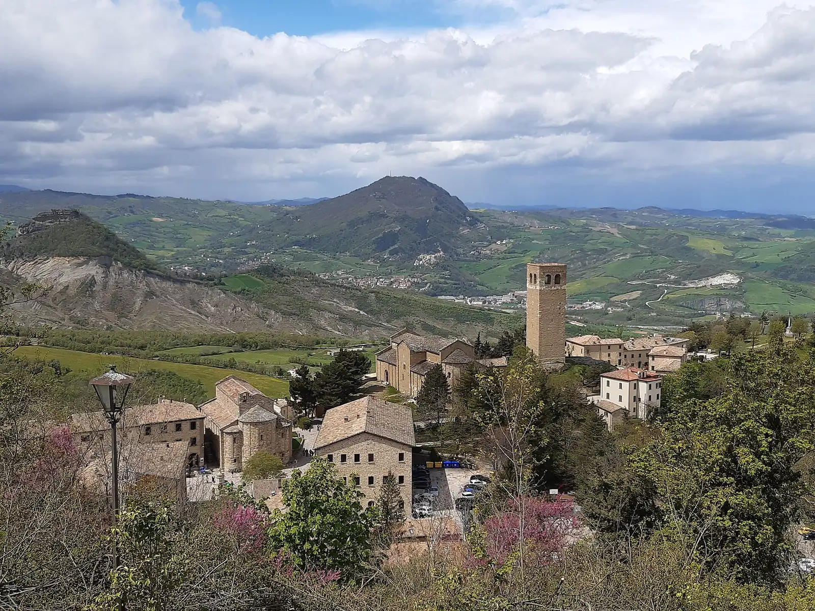 San Leo e la Valmarecchia viste dall'alto, con il campanile, le case in pietra e le colline verdi sullo sfondo