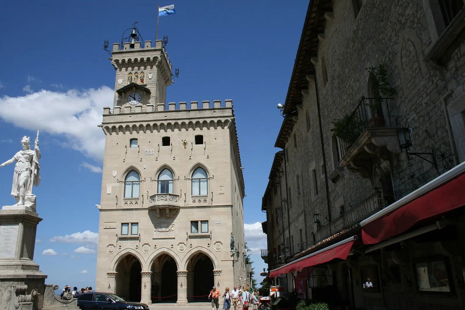 Le Palazzo Pubblico de San Marino avec sa tour crénelée et la Statua della Libertà à gauche, sous un ciel bleu