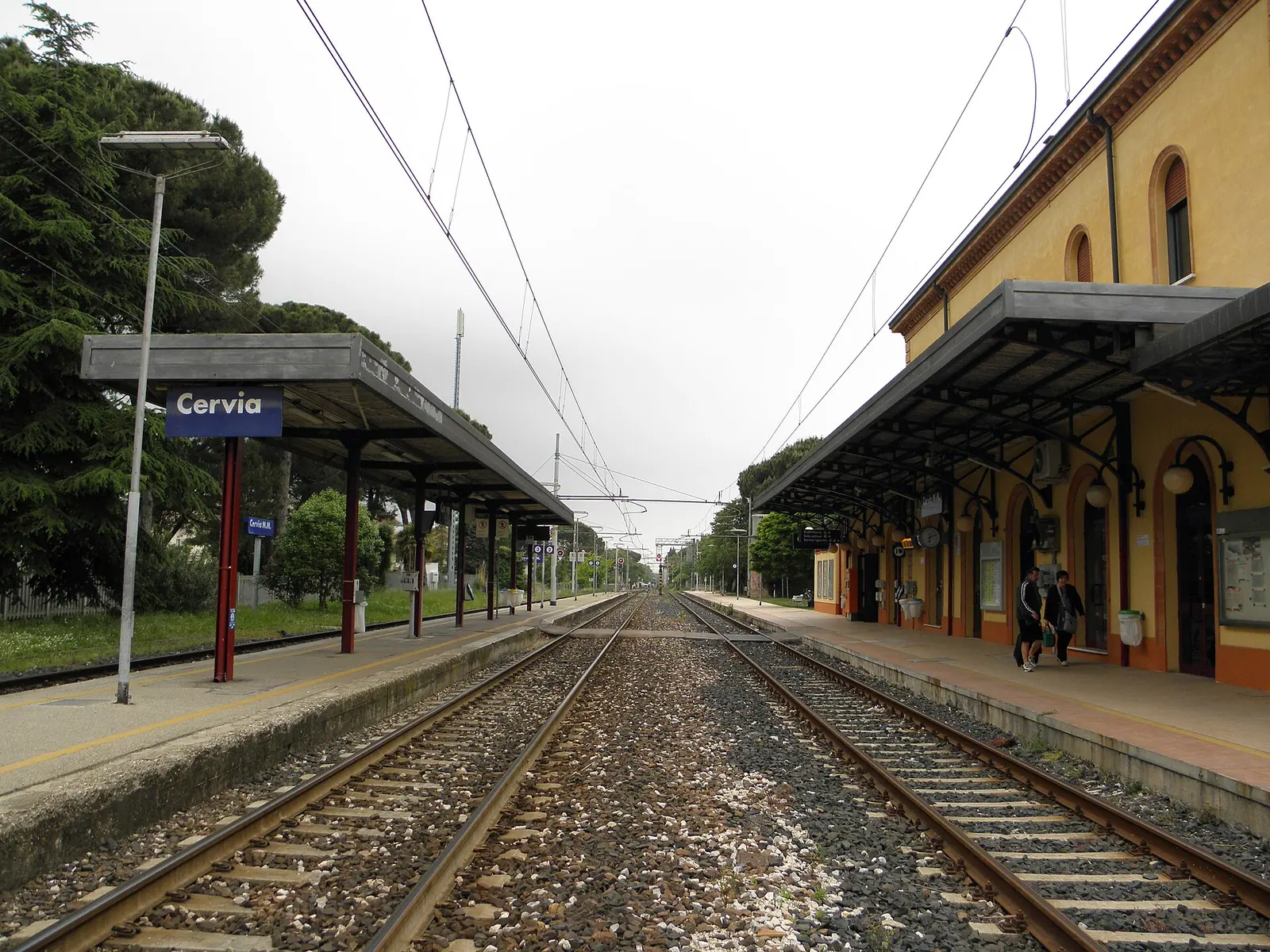The tracks and platforms at Cervia-Milano Marittima station, with the “Cervia” sign, canopies and yellow building