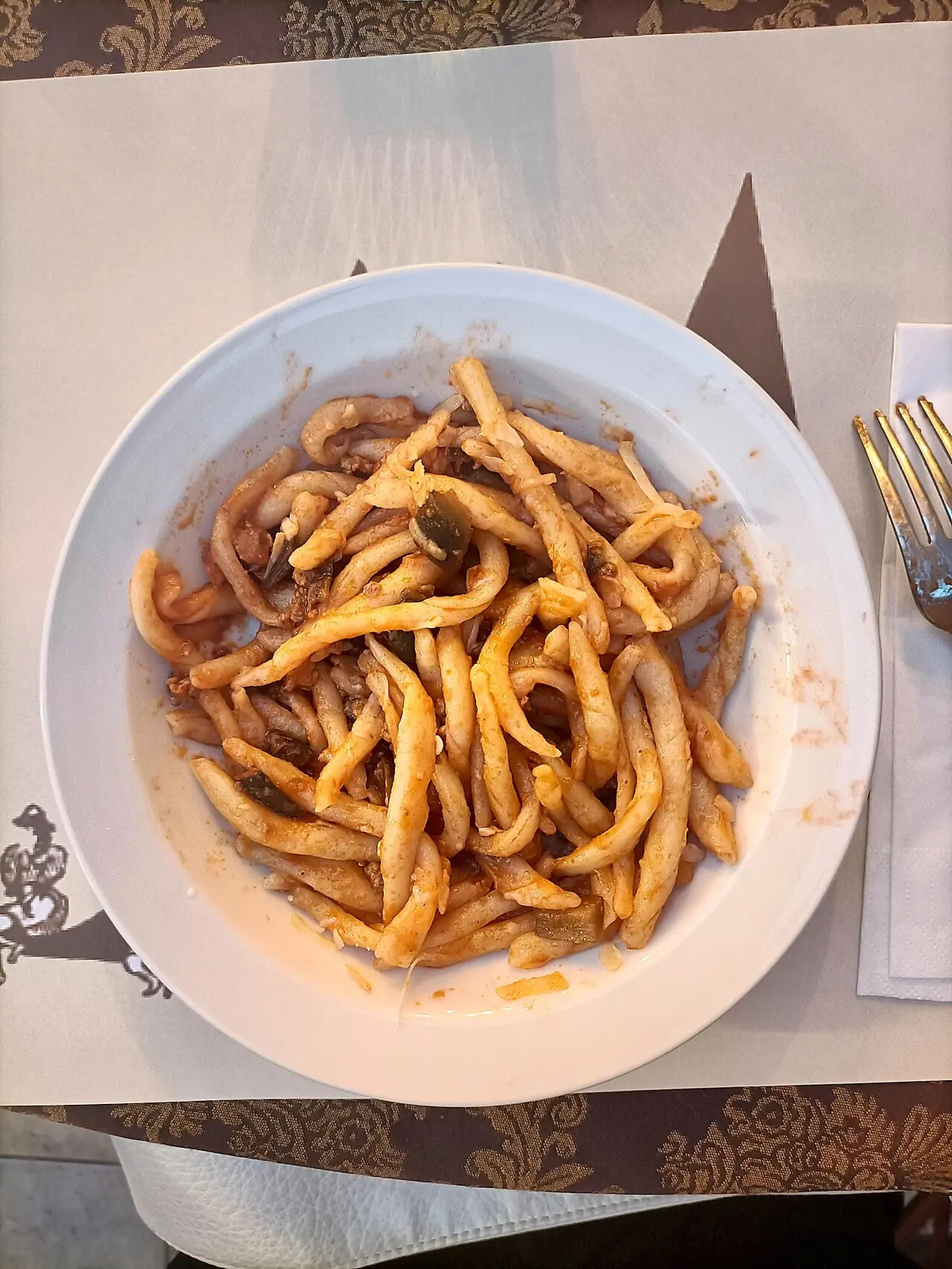 Strozzapreti mit Auberginen und Salsiccia auf einem weißen Teller