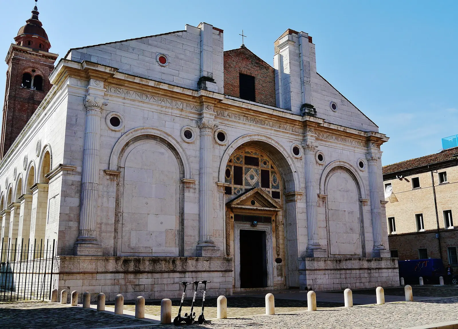 La facciata in marmo del Tempio Malatestiano di Rimini ripresa di tre quarti, con il campanile in mattoni a sinistra