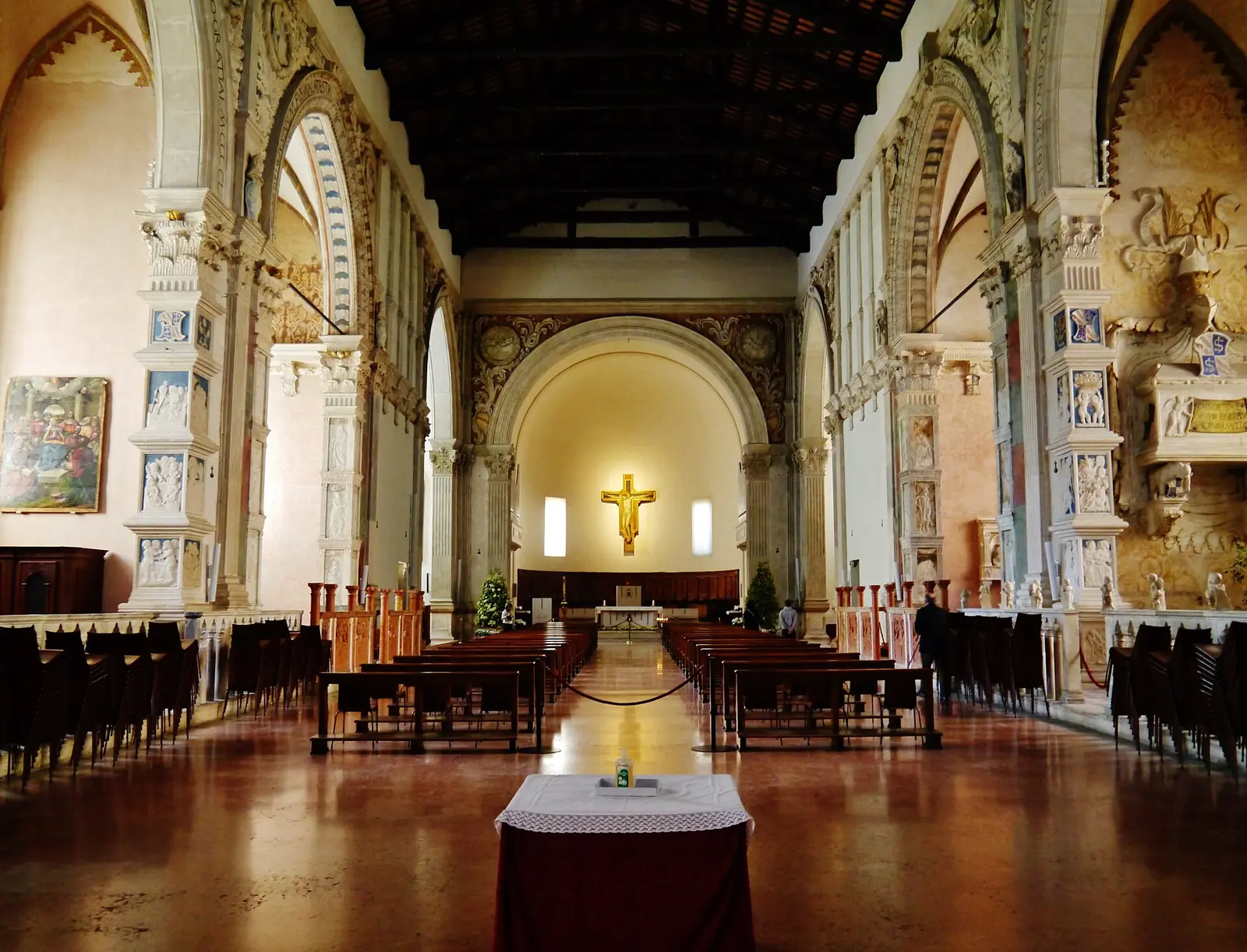 Das Kirchenschiff des Tempio Malatestiano in Rimini in Richtung Apsis mit den skulpturengeschmückten Seitenkapellen und dem goldenen Kruzifix