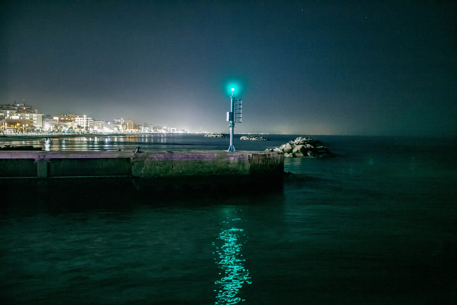 Il molo di Bellaria di notte con il fanale verde acceso e le luci della costa in lontananza