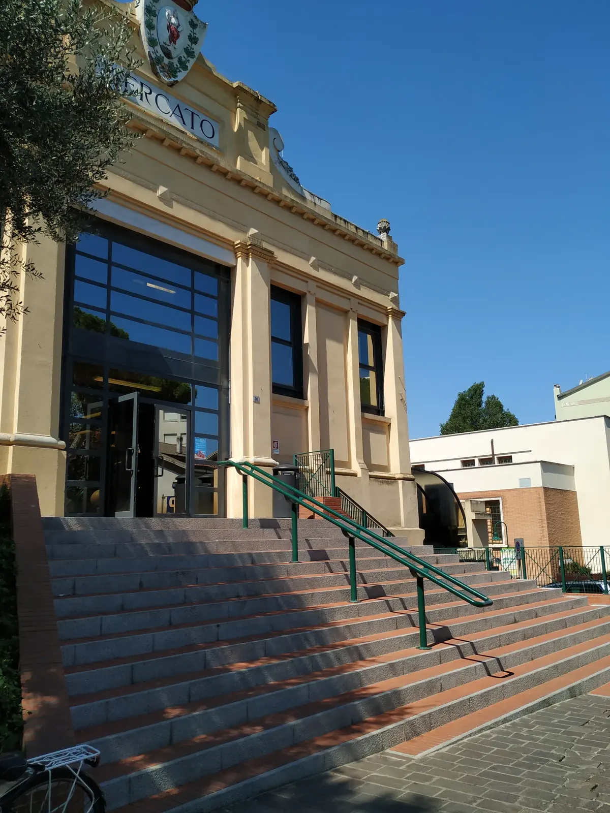 La scalinata d'ingresso del Mercato coperto di Cattolica, con il corrimano verde e la facciata gialla
