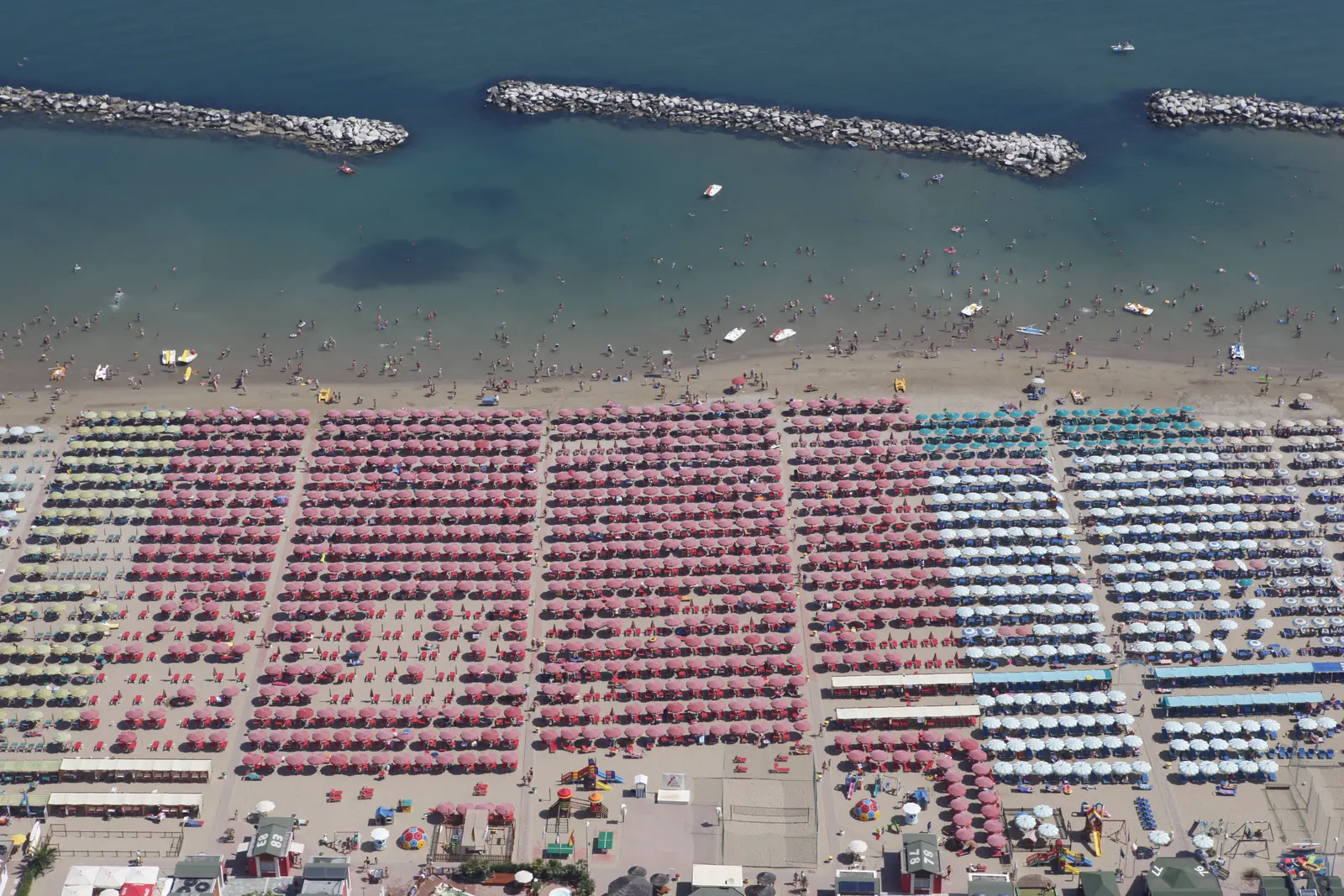 La spiaggia di Cattolica dall'alto, con le file di ombrelloni rossi e bianchi, il mare e le scogliere