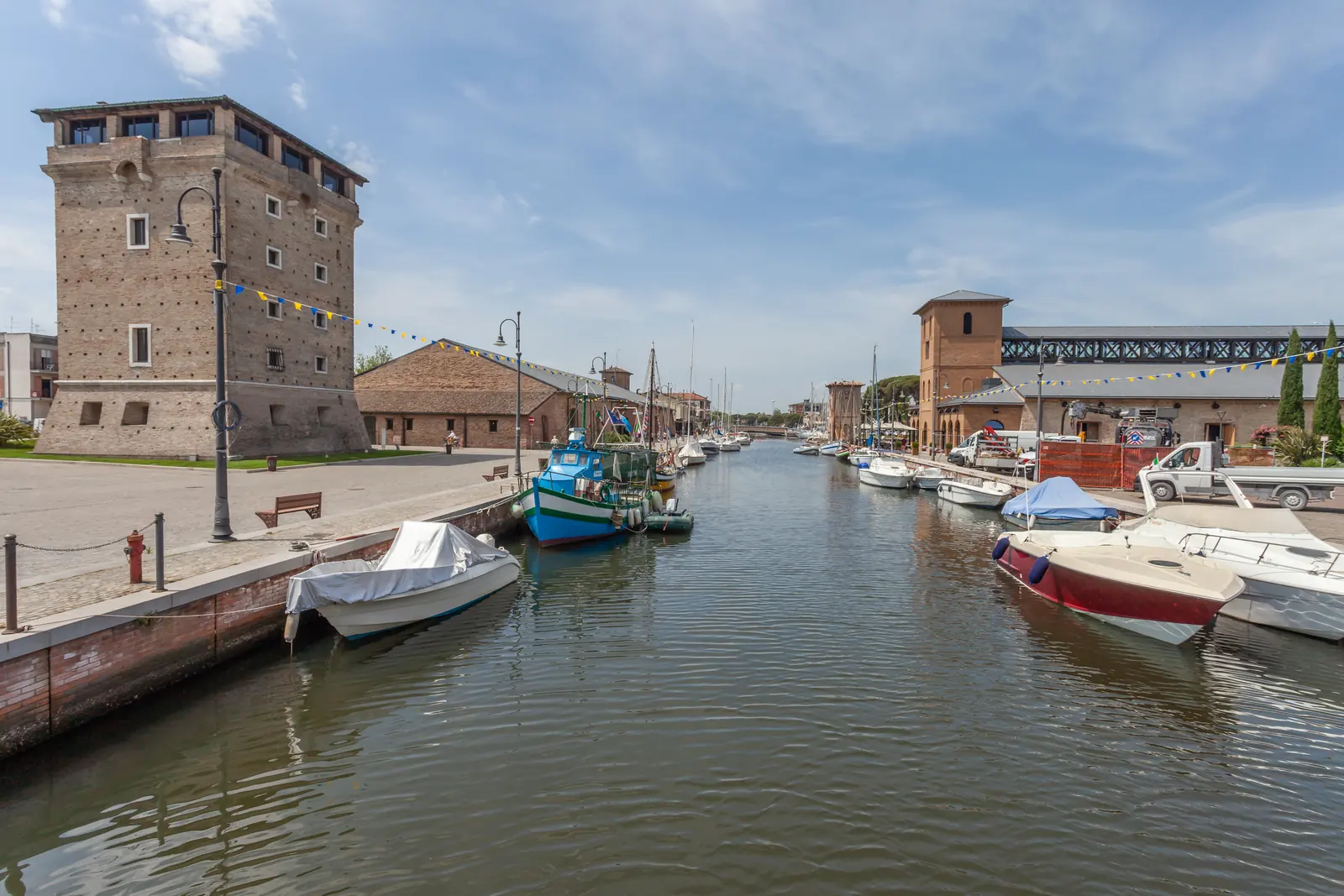 Il porto canale di Cervia con la Torre San Michele, le barche ormeggiate e un magazzino del sale in fondo