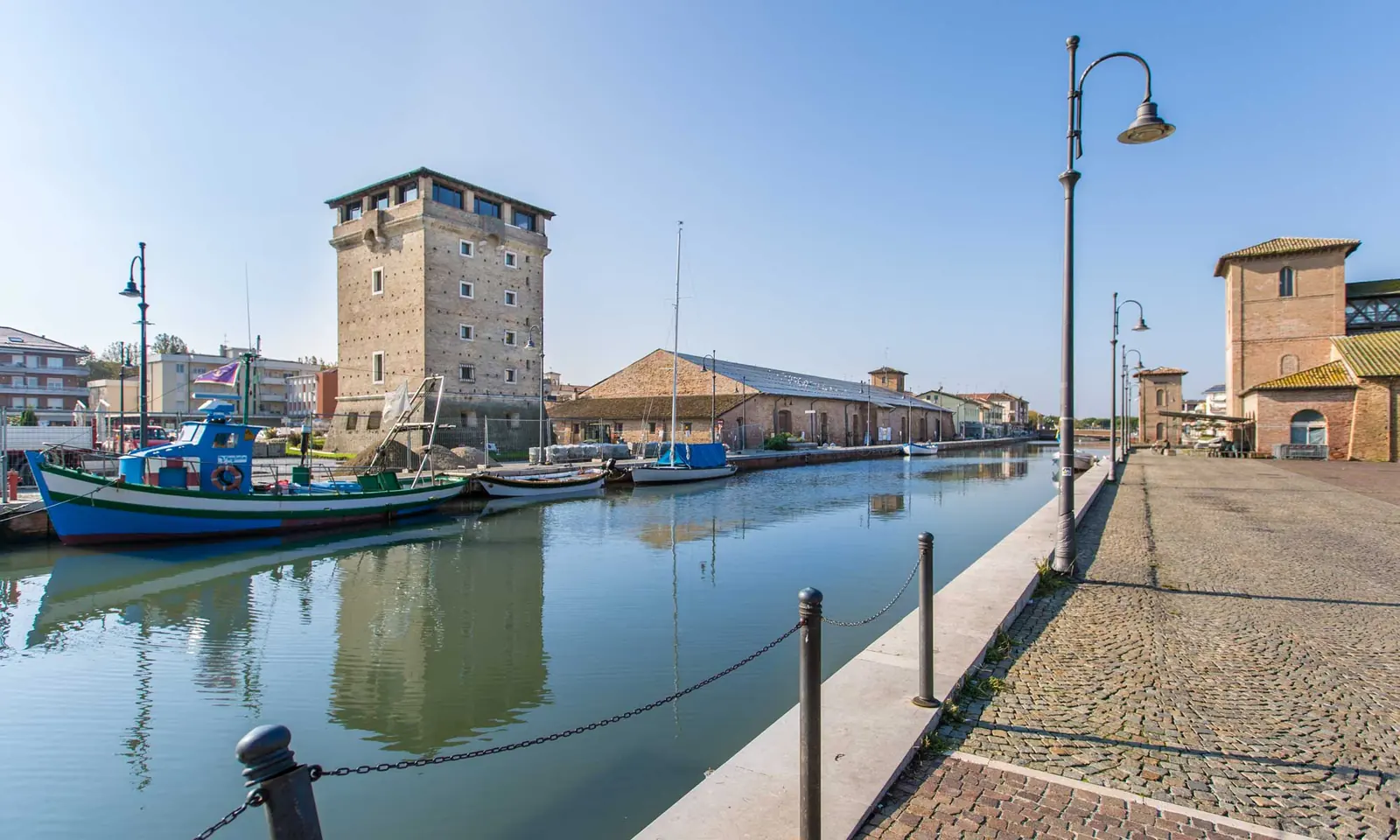 La Torre San Michele sul porto canale di Cervia, con le barche ormeggiate e la banchina lastricata