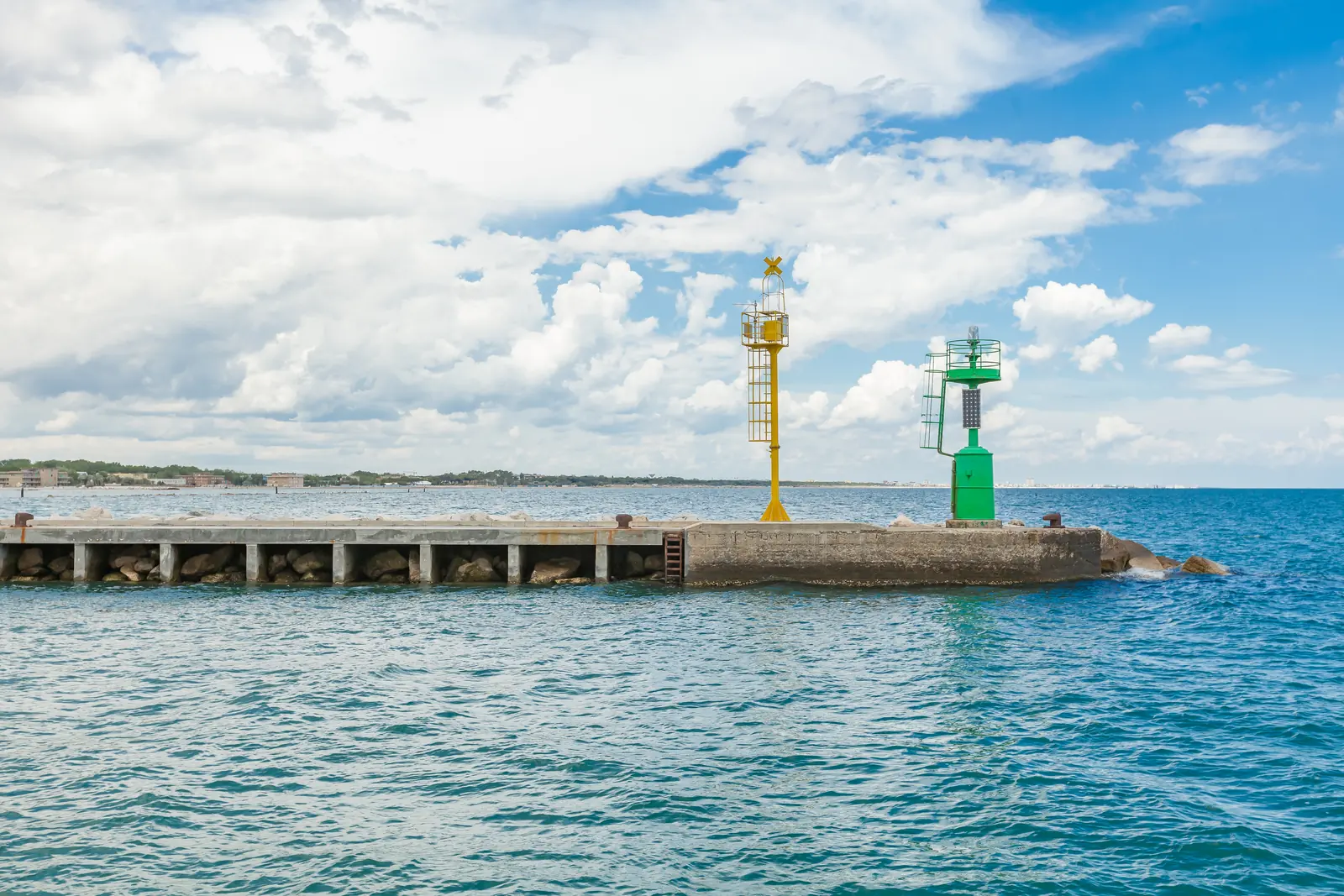 Il molo del porto canale di Cesenatico con il fanale verde e il segnale giallo, sul mare azzurro