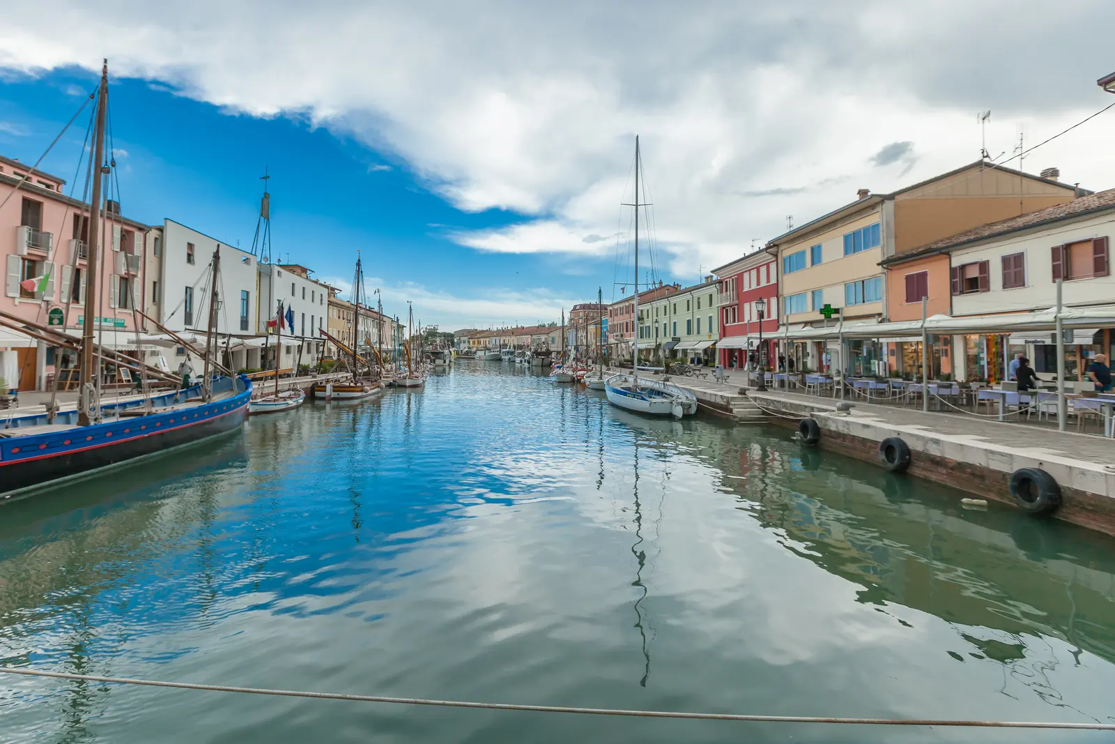 Il porto canale leonardesco di Cesenatico con le case colorate, una barca storica e l'acqua calma