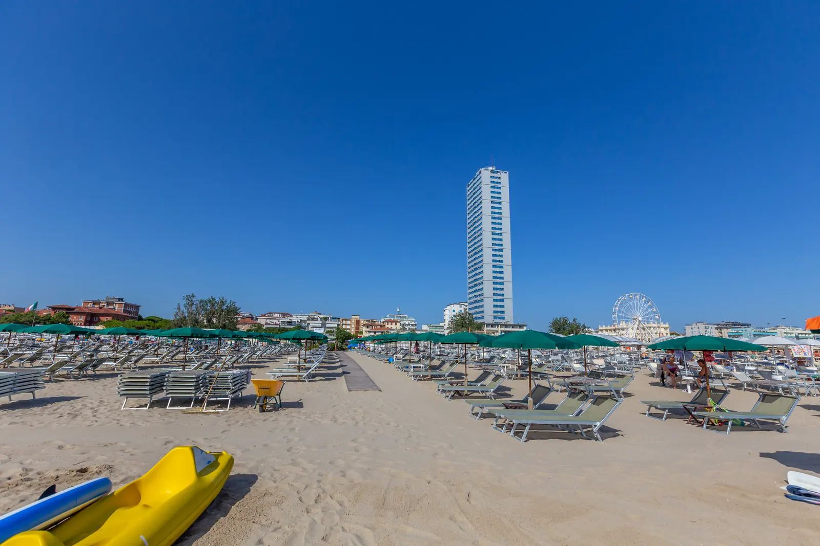 La spiaggia di Cesenatico con gli ombrelloni verdi chiusi, il Grattacielo e la ruota panoramica