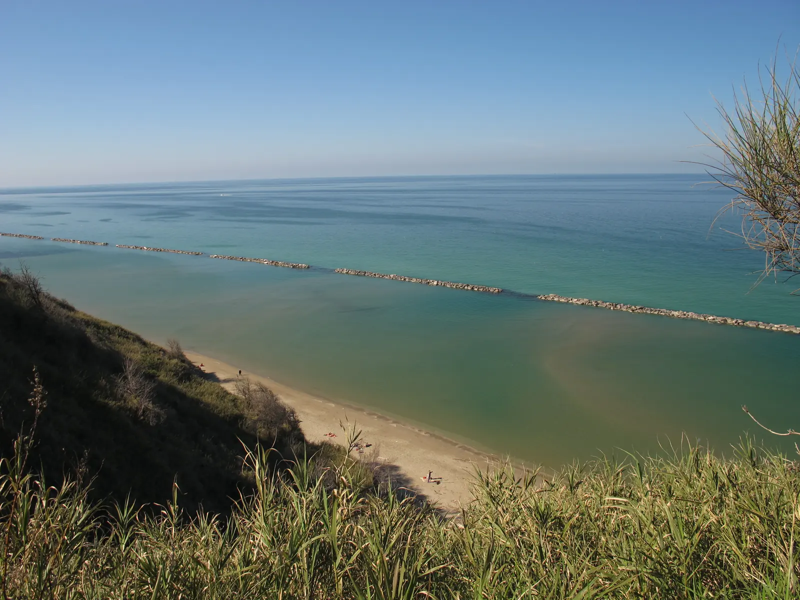 La spiaggia di Fiorenzuola di Focara vista dalla falesia, con le scogliere e il mare verde