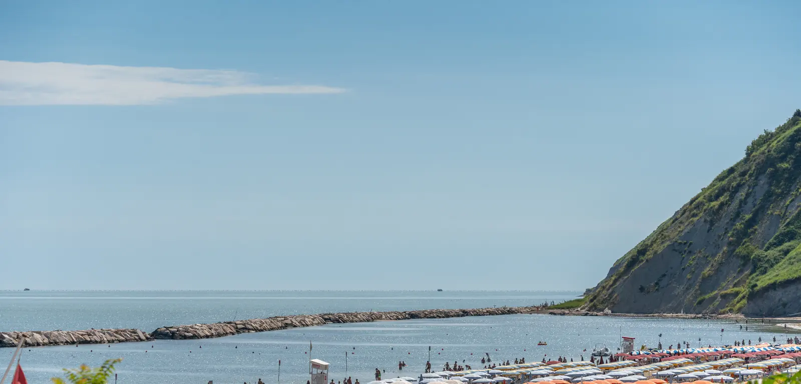 La spiaggia di Gabicce Mare con gli ombrelloni colorati, la scogliera e il promontorio di Gabicce Monte