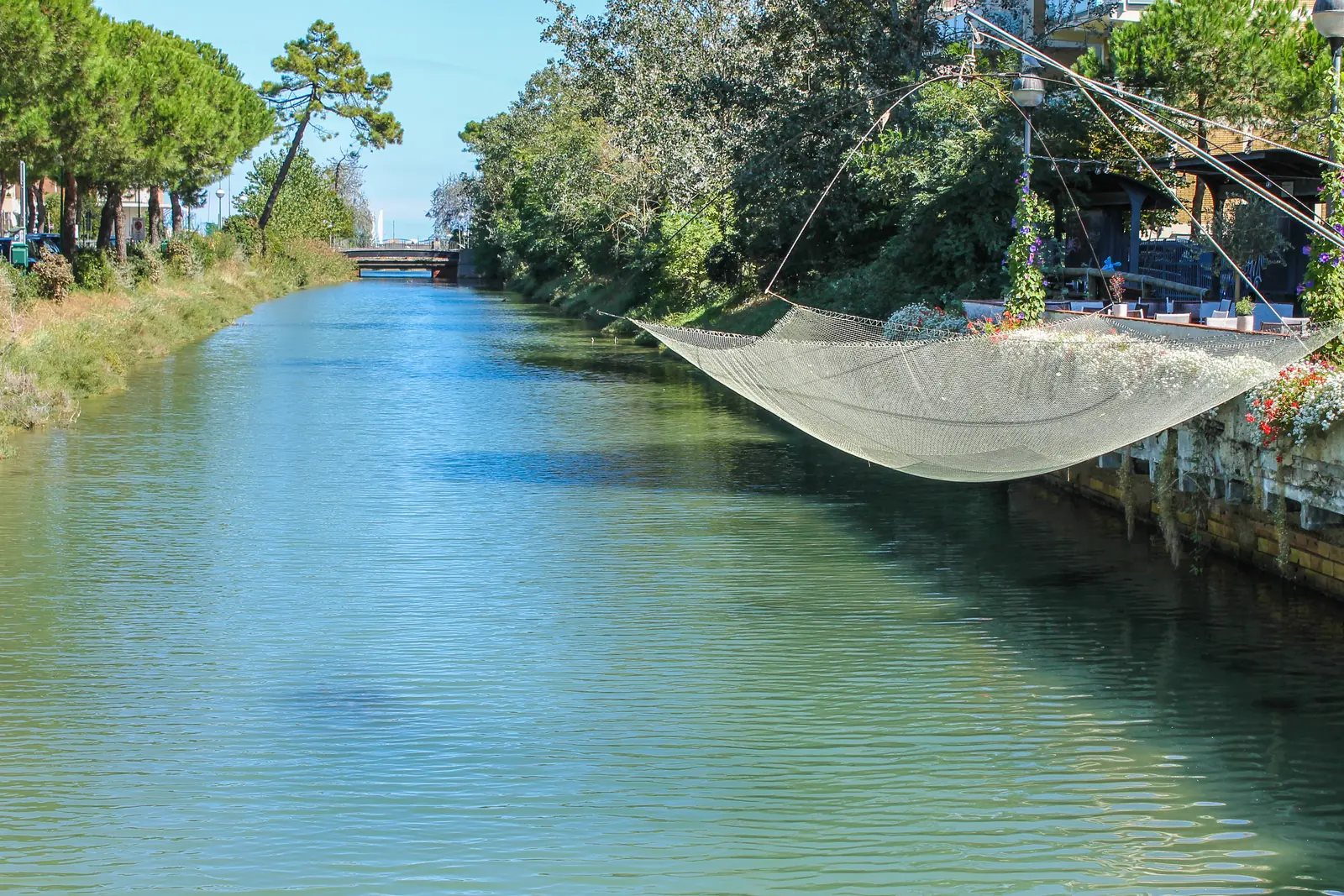 Il Canalino di Milano Marittima fra i pini, con una bilancia da pesca sospesa sull'acqua