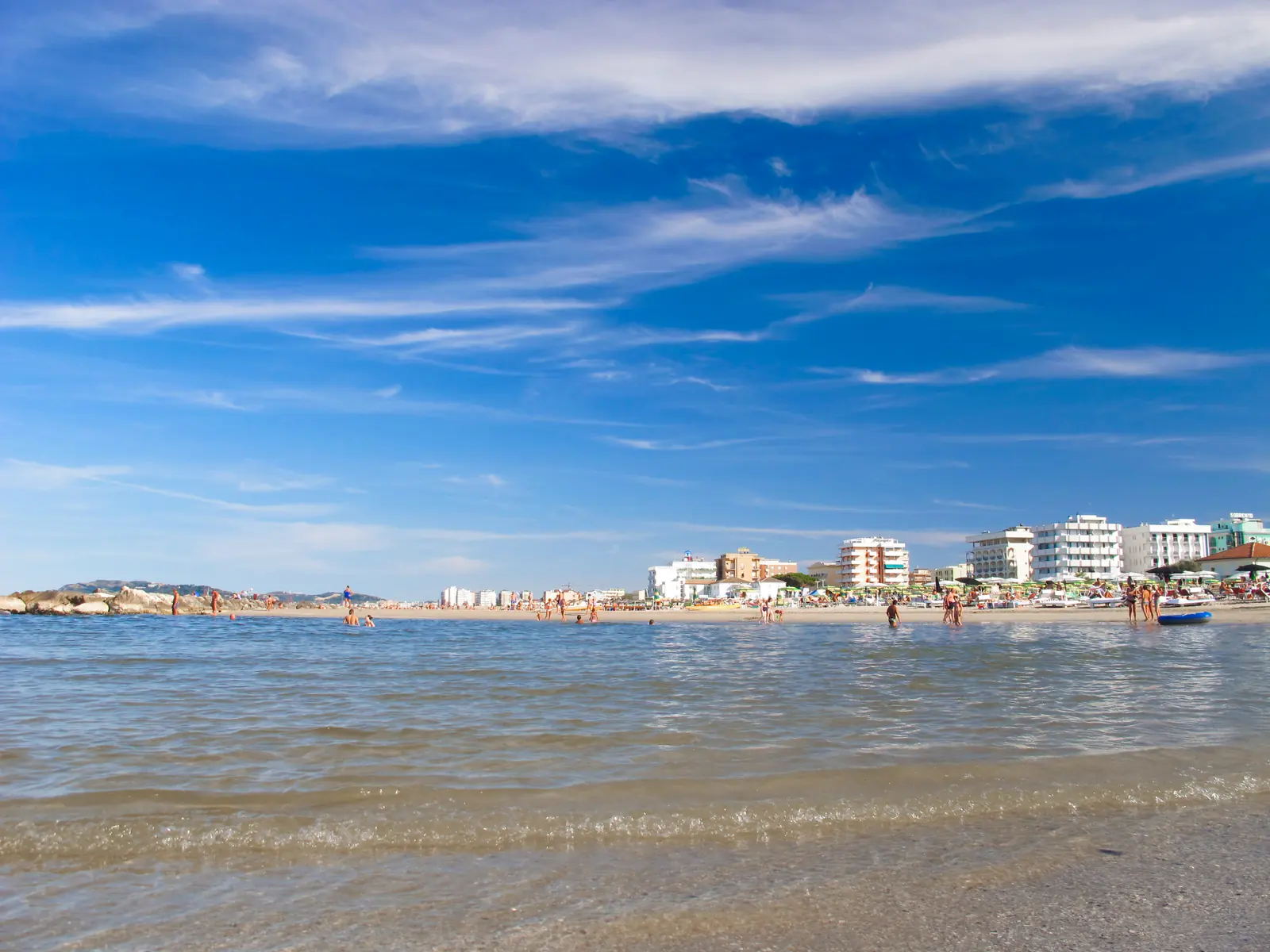 Il mare calmo di Misano Adriatico con i bagnanti, la spiaggia e i palazzi del lungomare