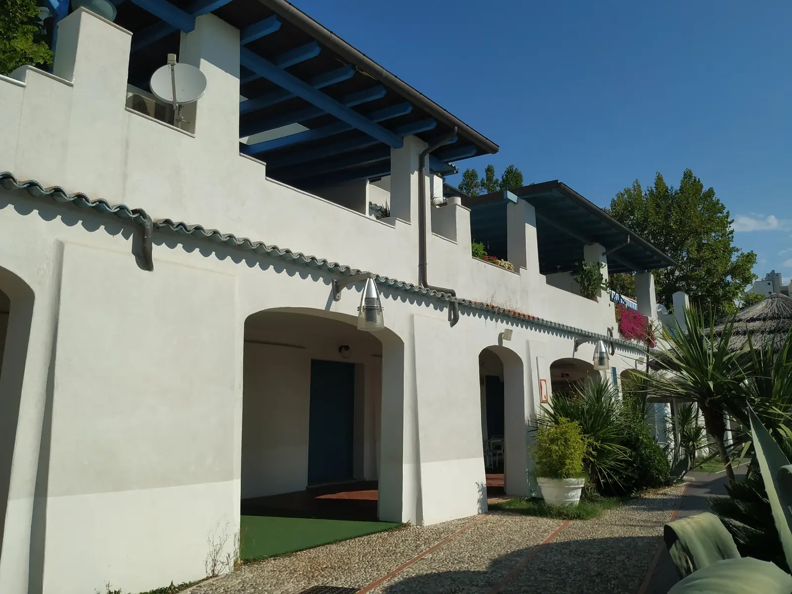 Le case bianche di Portoverde con i portici, le terrazze e le travi azzurre, fra le palme