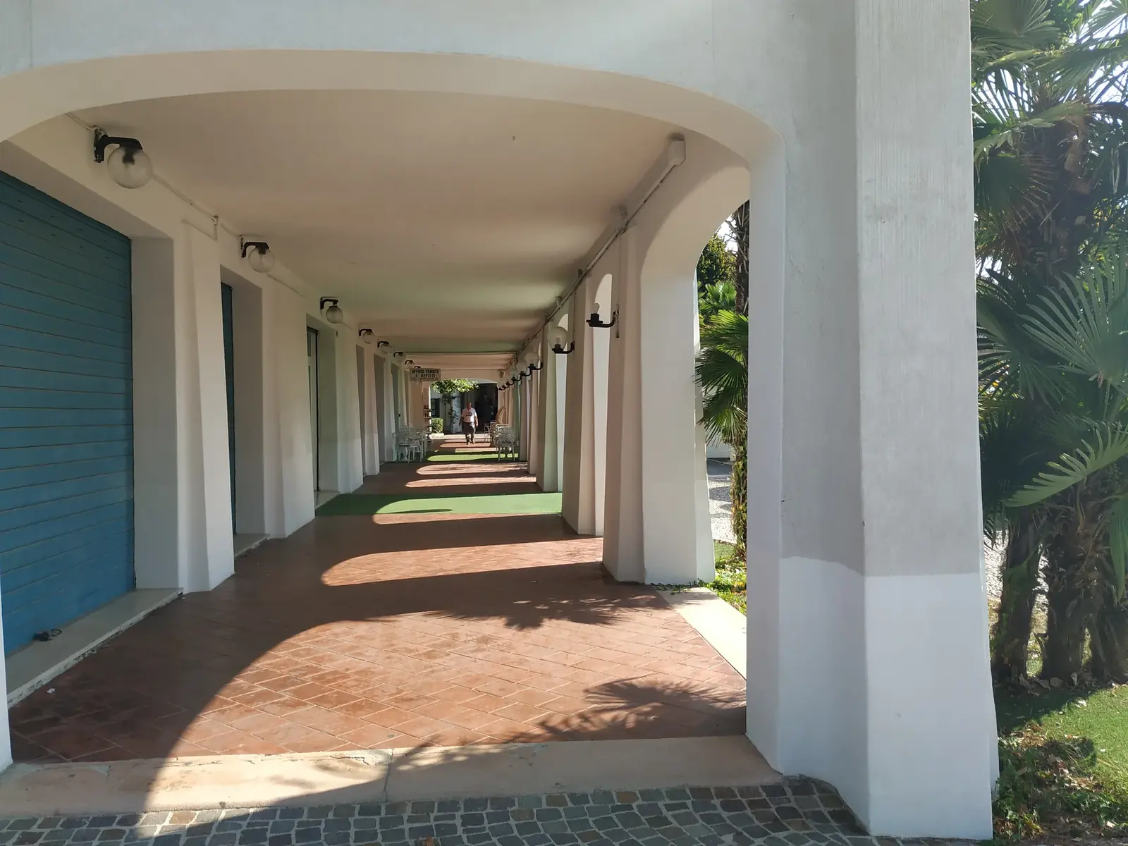 Un porticato bianco di Portoverde, con le arcate in fila e il pavimento in cotto