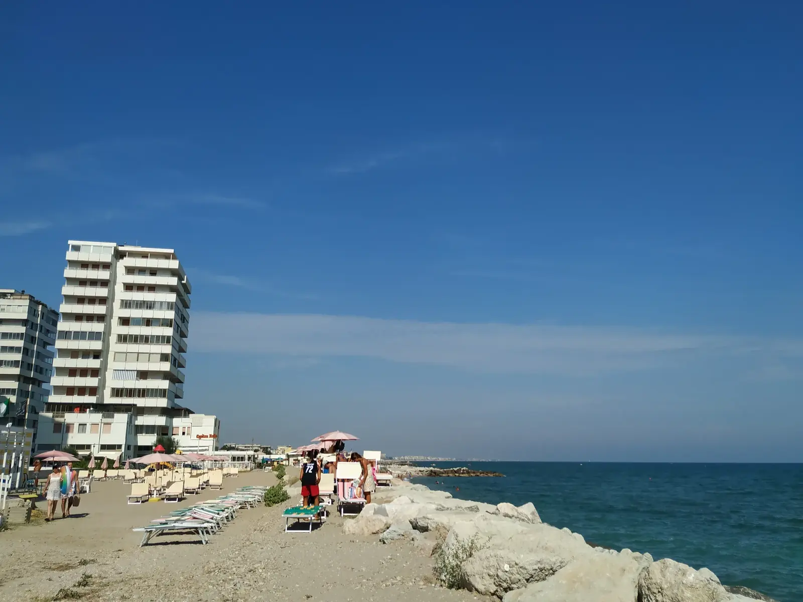 La spiaggia di Portoverde con la scogliera, i lettini e i palazzi alti affacciati sul mare