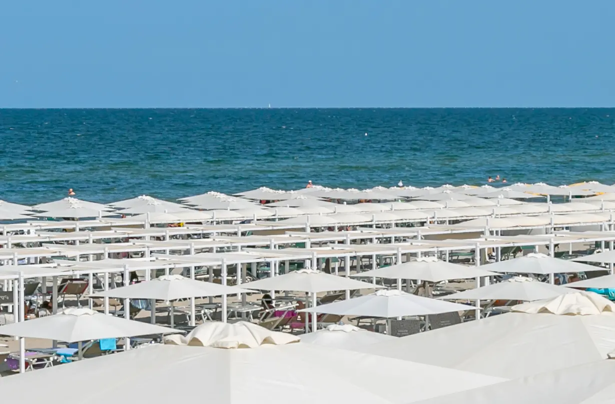 Le file di ombrelloni e di tende bianche sulla spiaggia di Riccione, davanti al mare blu