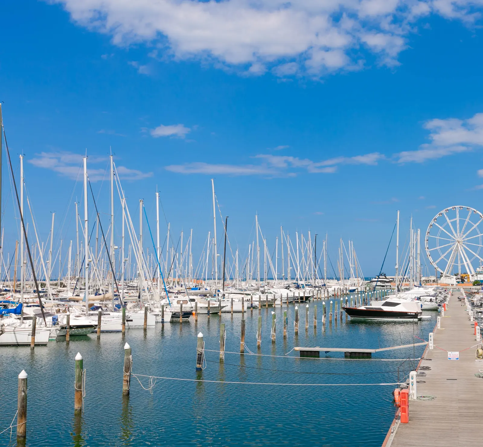 La darsena di Rimini con le barche a vela ai pontili e la ruota panoramica sullo sfondo