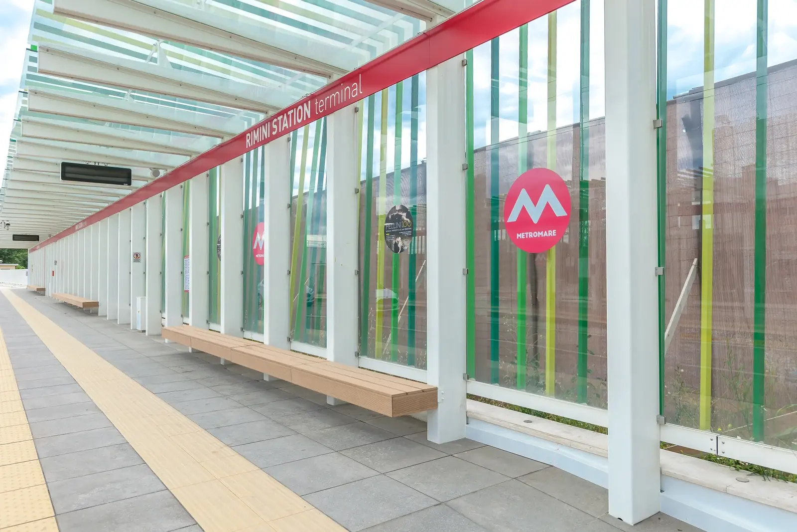 La banchina del Metromare alla stazione di Rimini, con la guida tattile gialla per le persone cieche e ipovedenti e la panca in legno