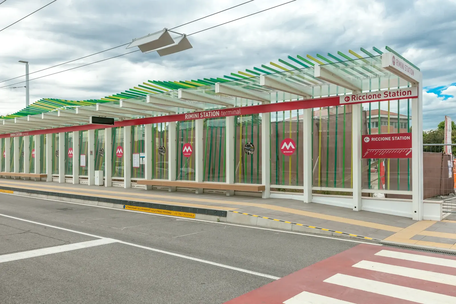 La fermata del Metromare davanti alla stazione di Rimini, con la pensilina a lamelle colorate e le strisce pedonali