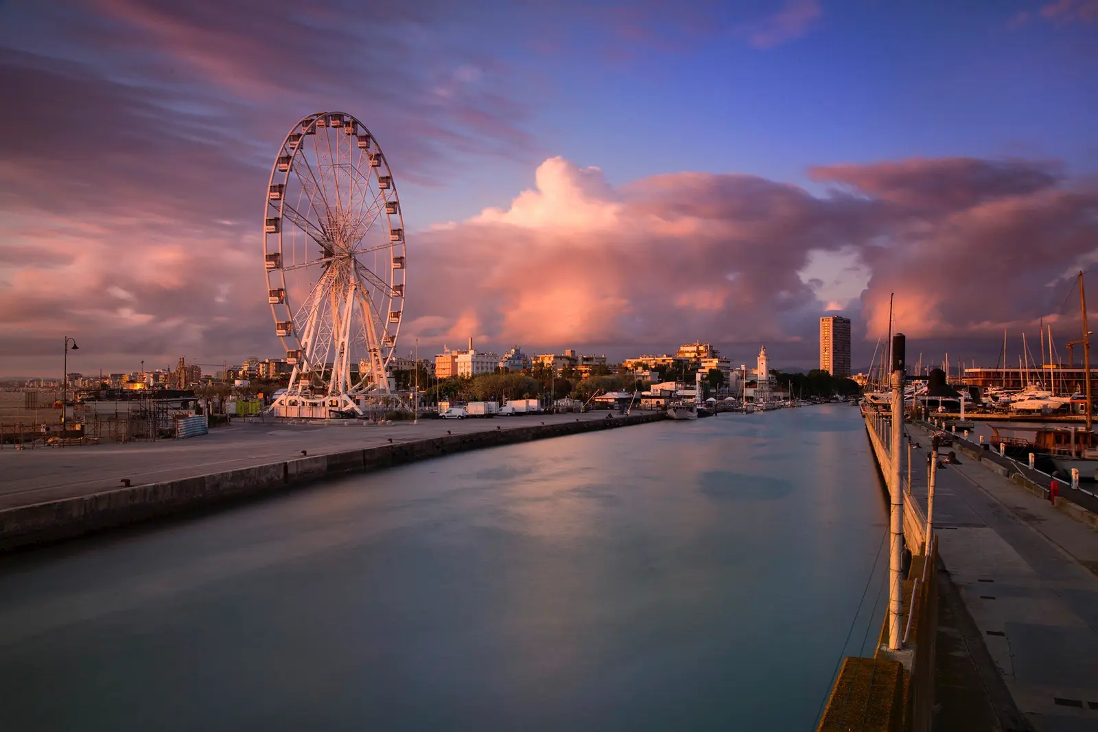 La ruota panoramica sul porto canale di Rimini al tramonto, con le nuvole rosa e la banchina vuota