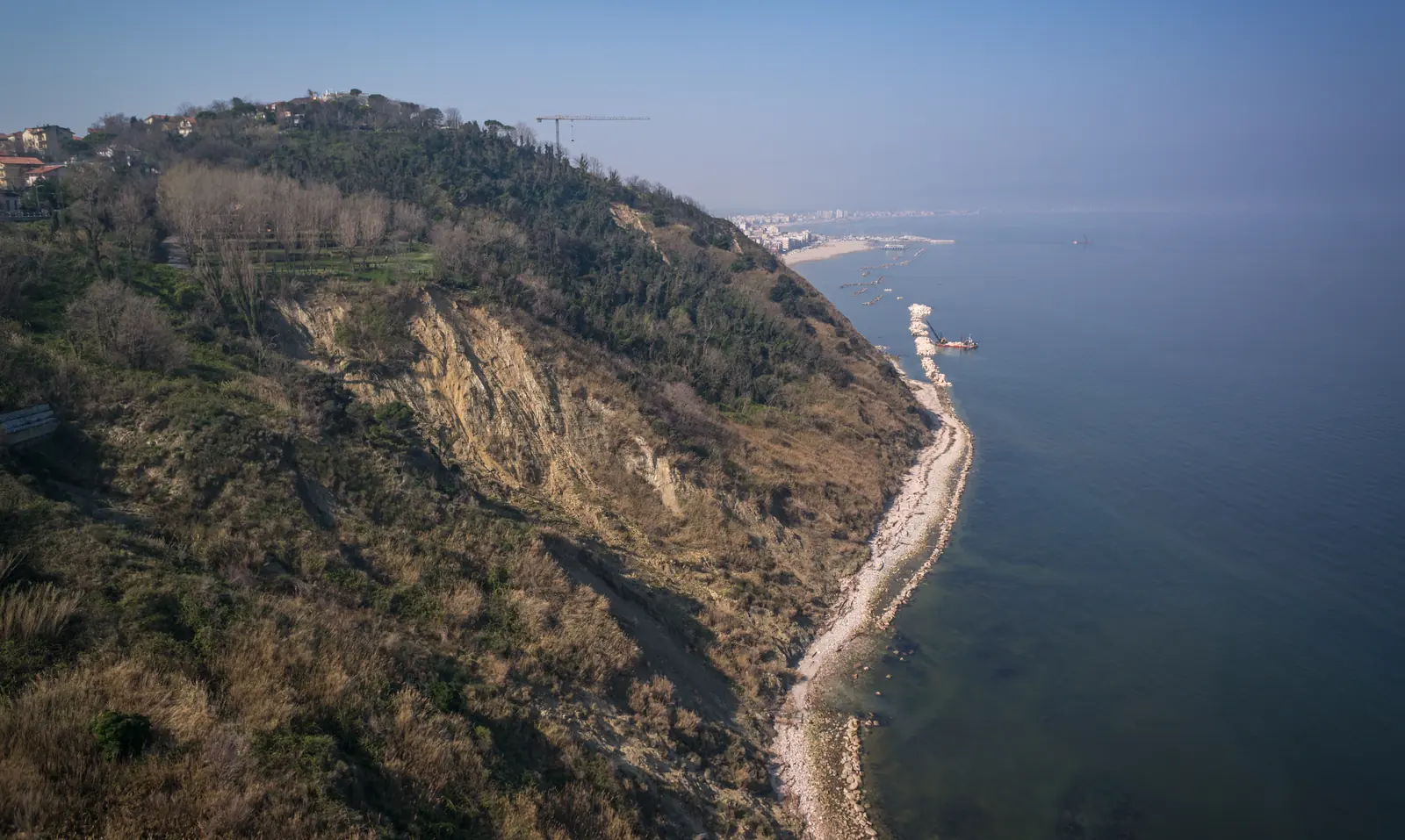 La falesia del Monte San Bartolo dall'alto, con la costa sassosa e Gabicce in lontananza